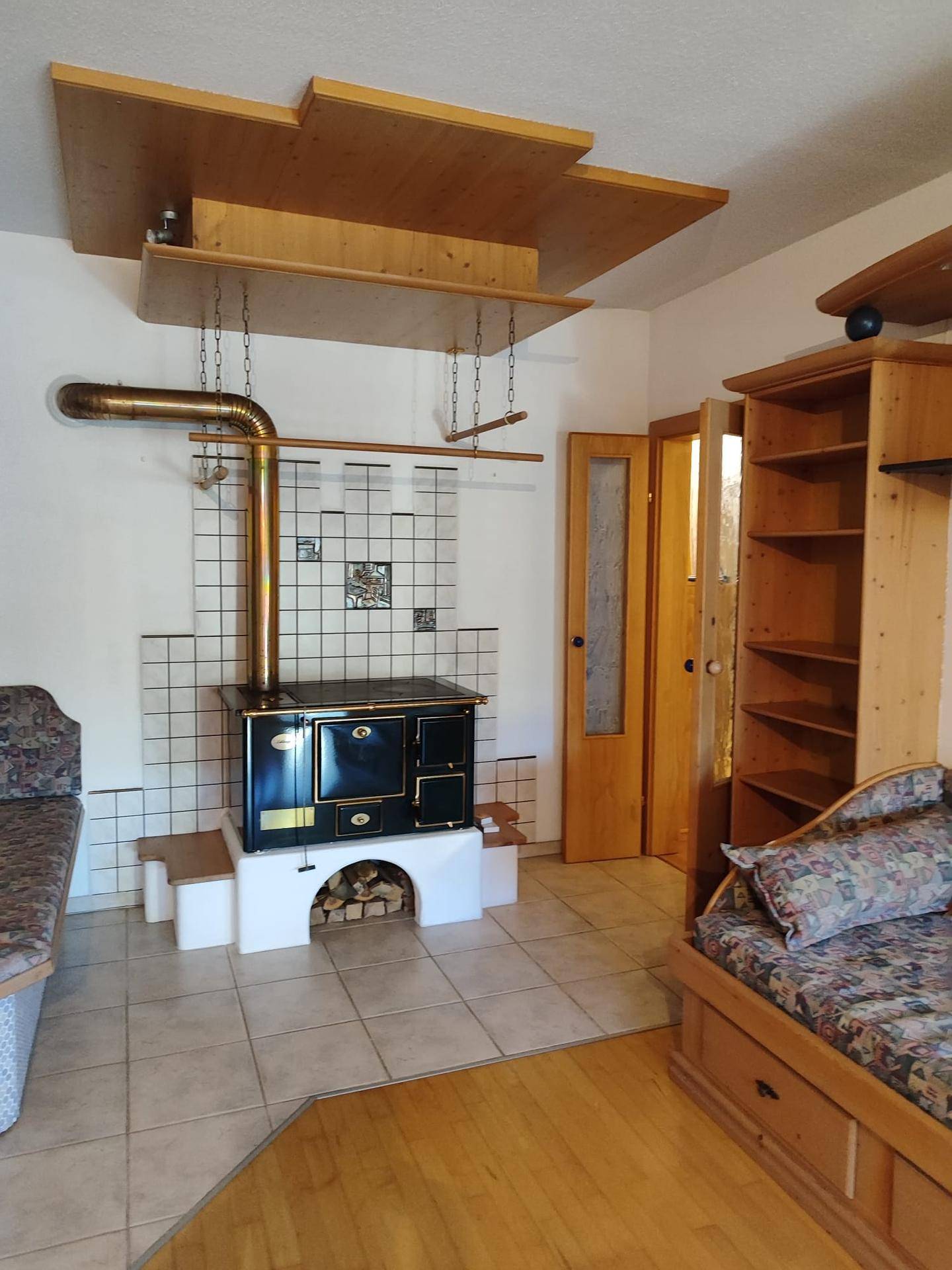 Gemütliches Wohnzimmer mit traditionellem Holzofen, Holzelementen und Sitzgelegenheiten.