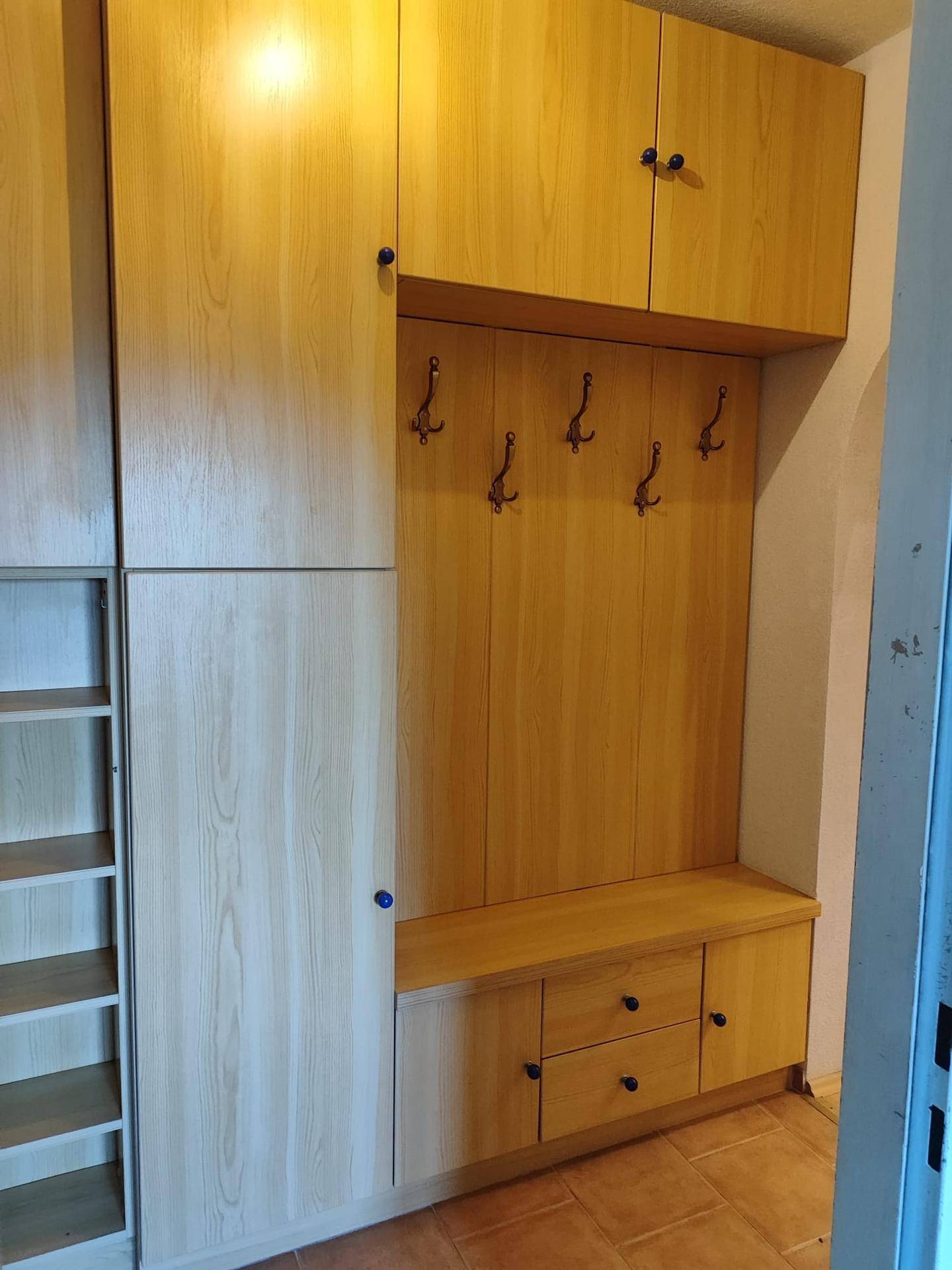 Eingangsbereich mit Garderobe, Sitzbank und Holzschränken.