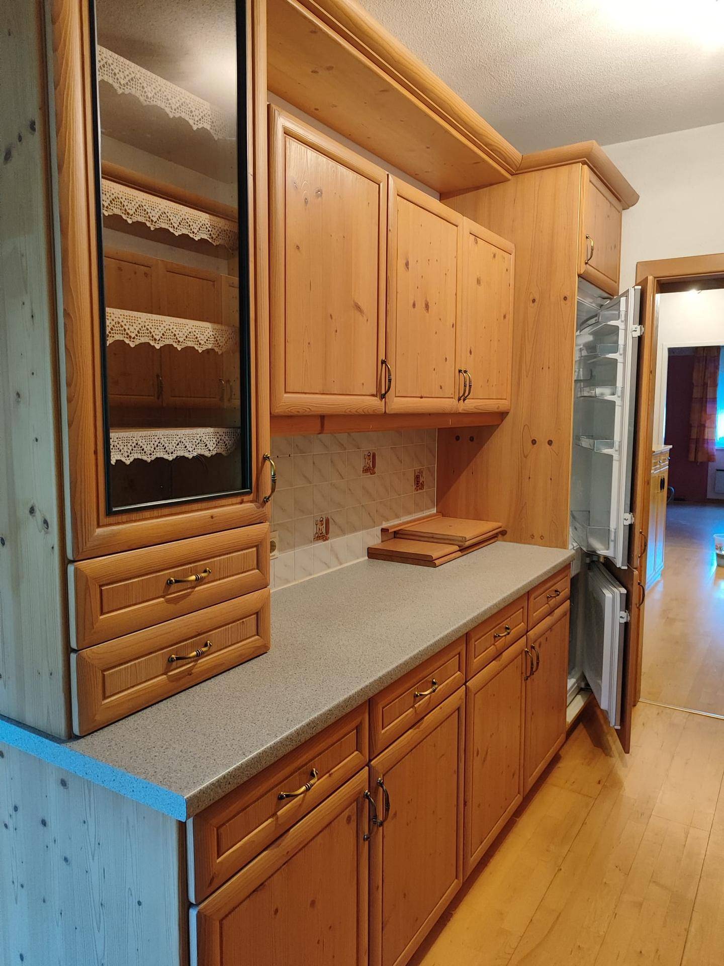 Traditionelle Holzküche mit Einbauschränken, Spüle und Kühlschrank.