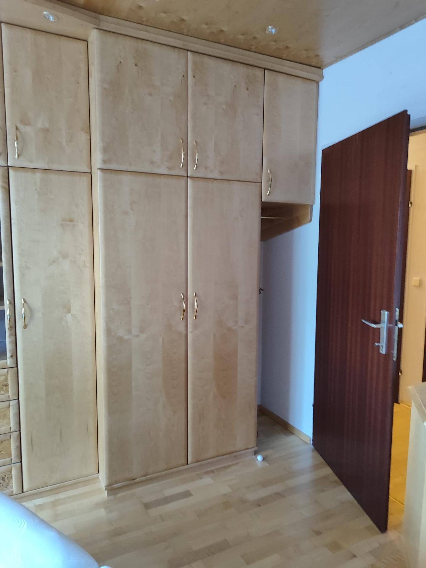 Großer Einbauschrank aus hellem Holz mit mehreren Türen und Schubladen.