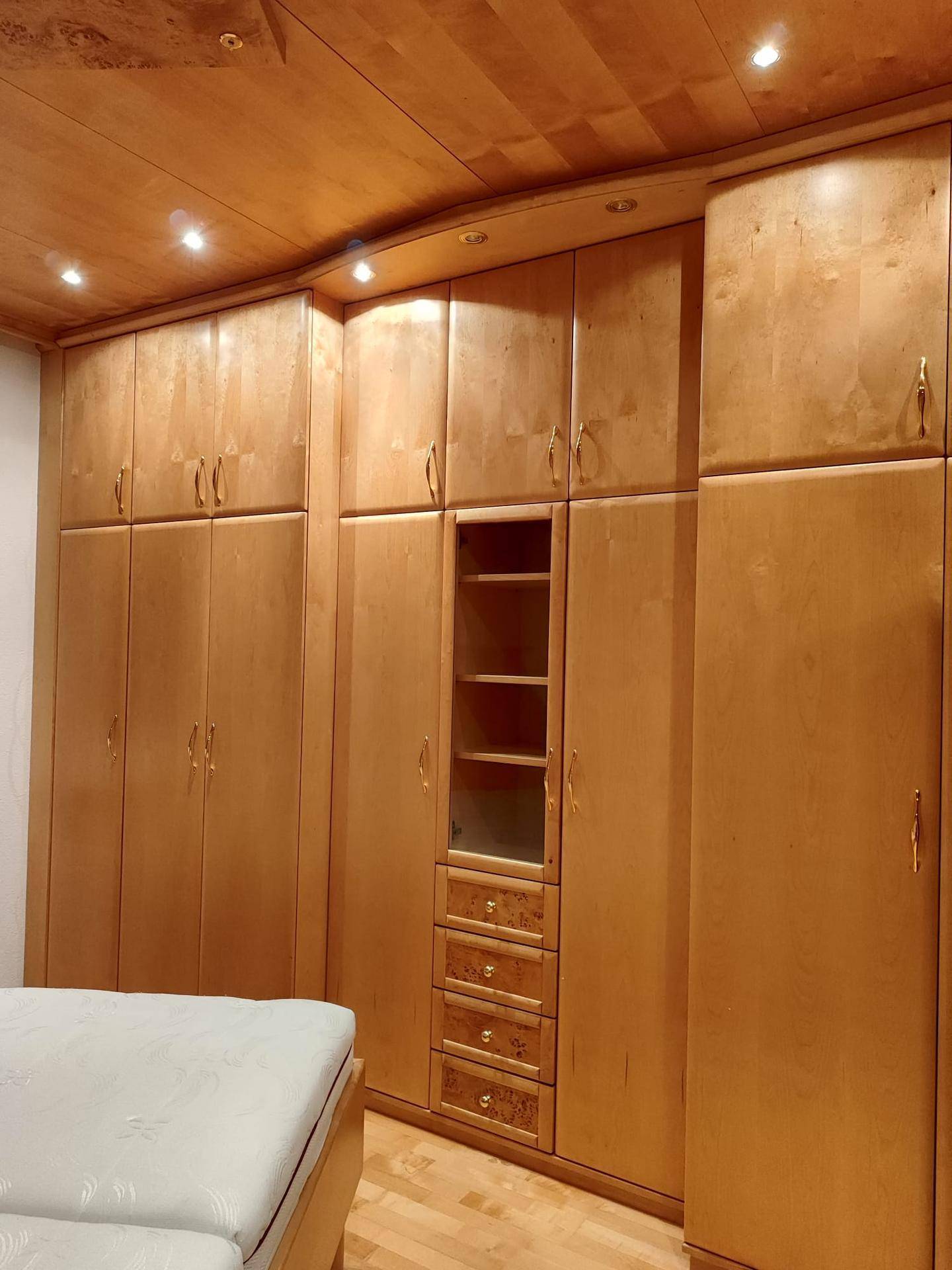 Geräumiger Schlafzimmerschrank aus hellem Holz mit vielen Fächern und Schubladen.