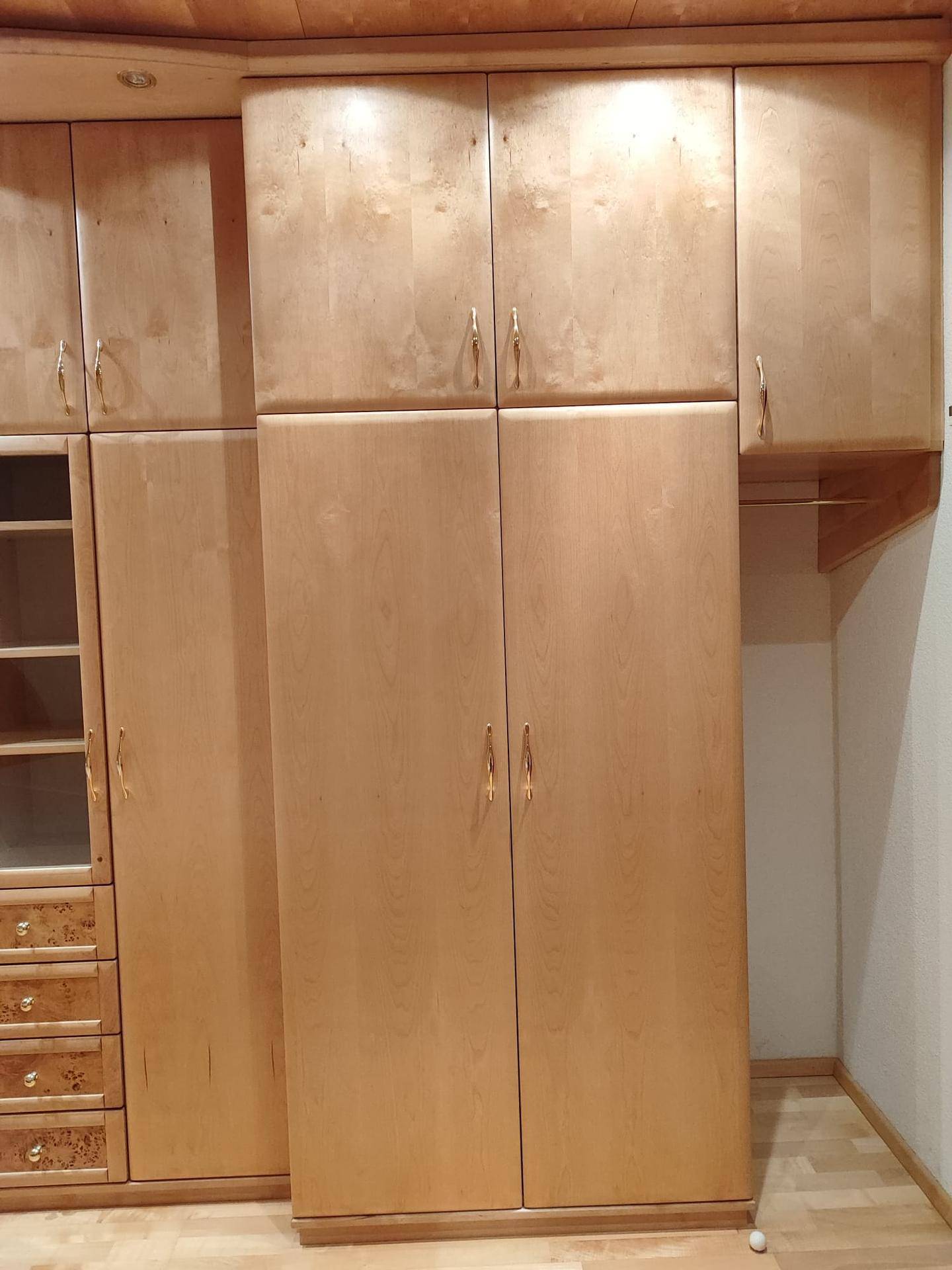 Großer Einbauschrank aus hellem Holz mit mehreren Türen und Schubladen.