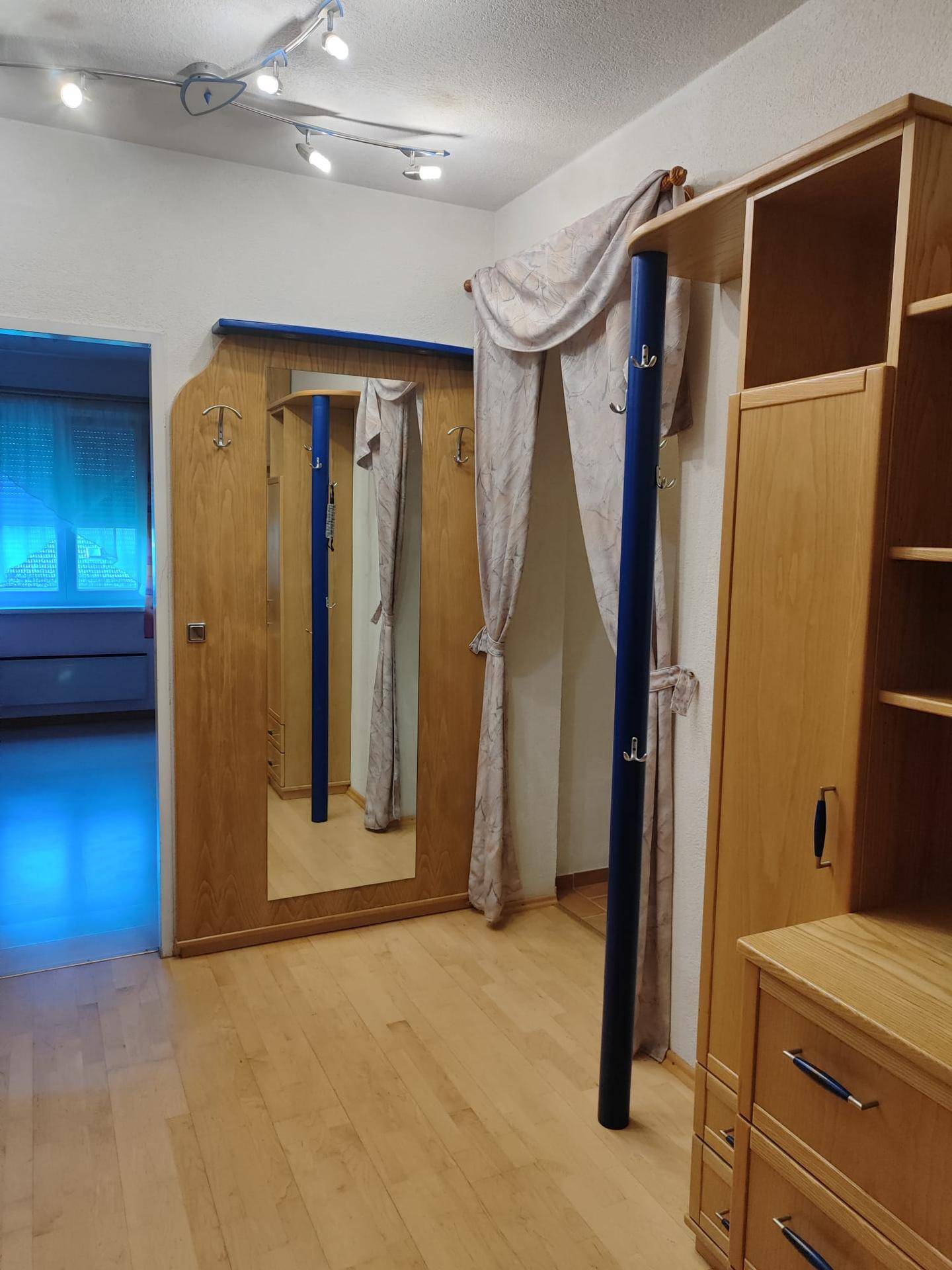 Eingangsbereich mit Garderobe, Spiegel und Holzboden.