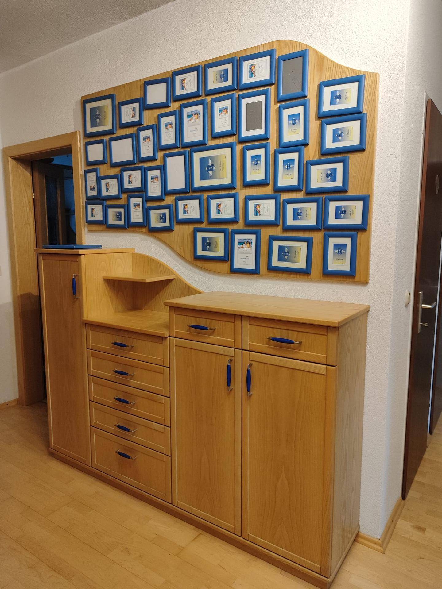 Flur mit Holzkommode, Schubladen und einer Wanddekoration mit vielen Rahmen.