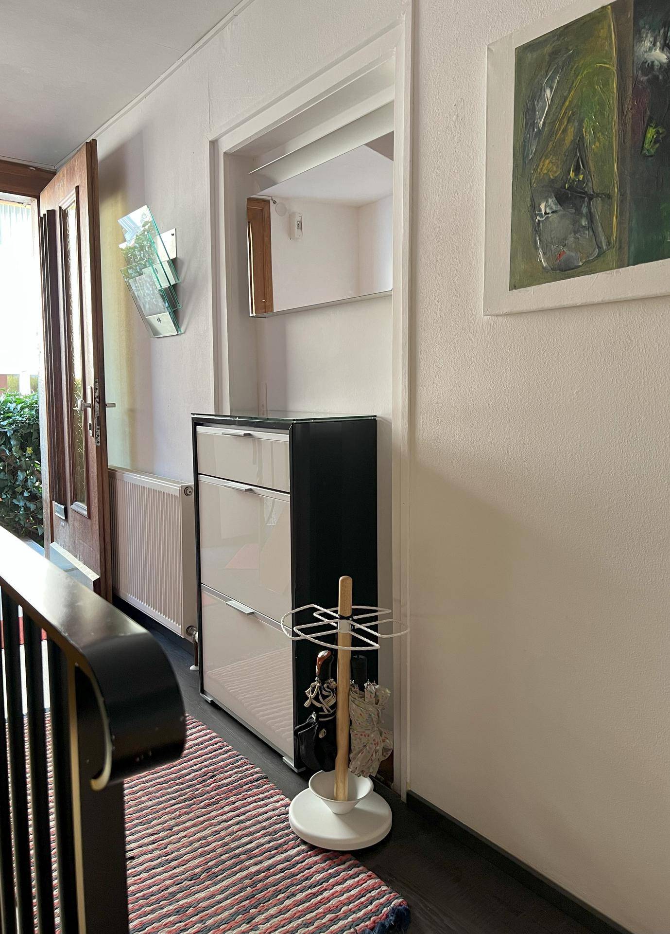 Heller Eingangsbereich mit Holzboden, Schuhschrank und Garderobe neben der Haustür.