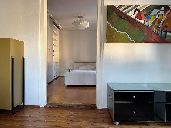 Blick in ein helles Schlafzimmer mit Holzboden, weißem Bett und integrierten Kleiderschränken.