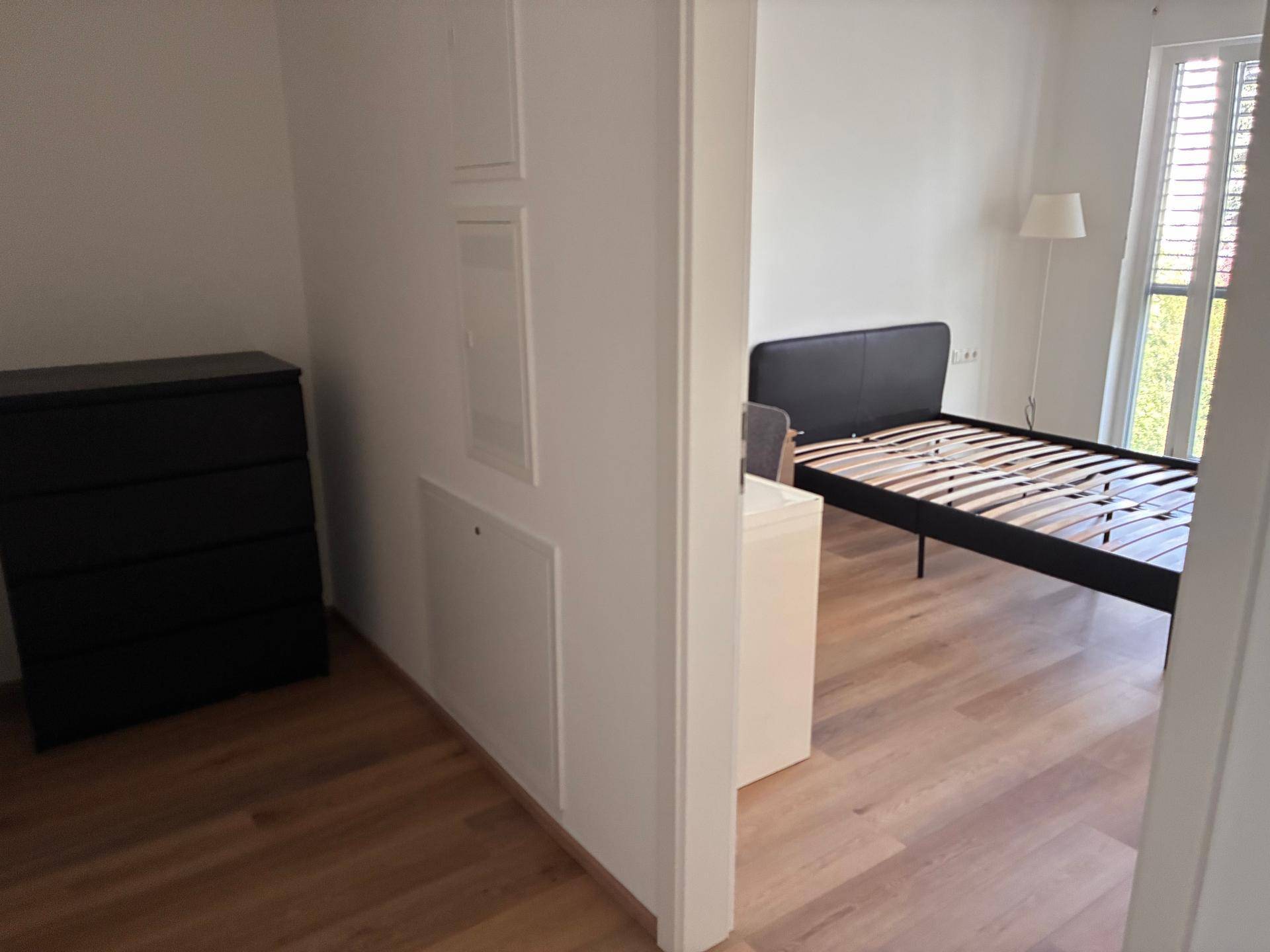 Blick in ein Schlafzimmer mit Parkettboden und einem Bettgestell.