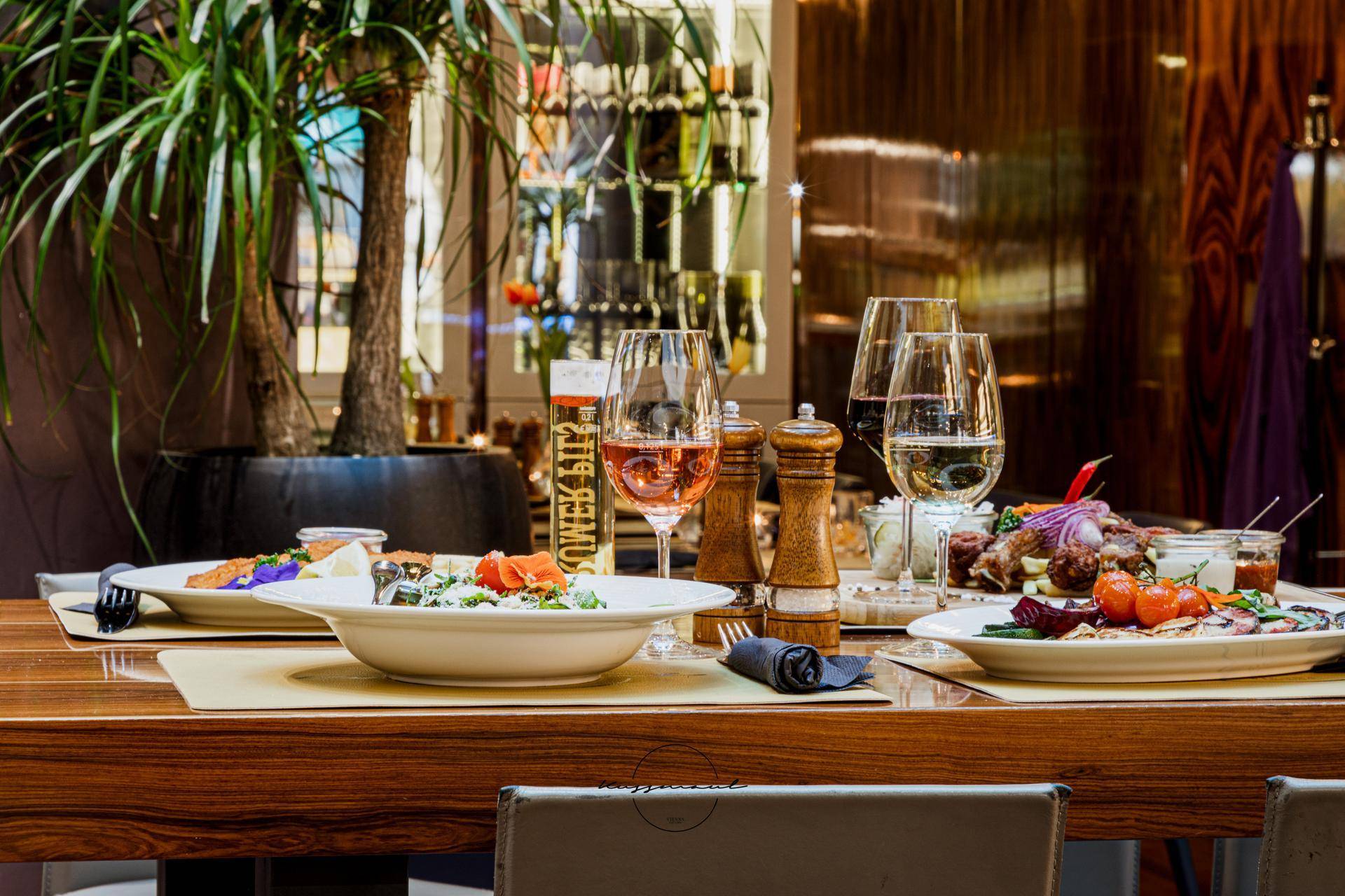 Nahaufnahme von appetitlichen Speisen und Getränken auf einem Holztisch in einem stilvollen Restaurantambiente.