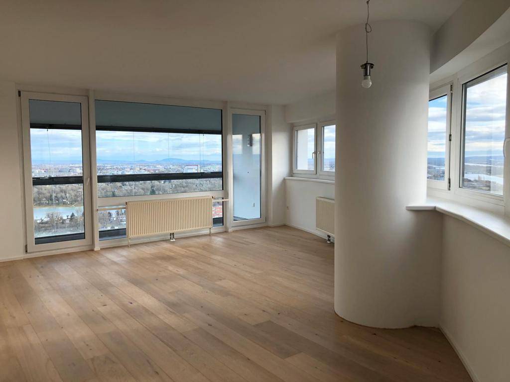 Helles Wohnzimmer mit Holzboden, großen Fenstern und weitem Blick über die Stadtlandschaft.