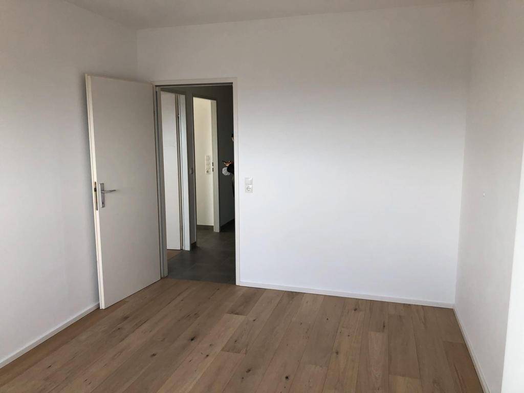 Leeres Schlafzimmer mit Holzboden und weiß gestrichenen Wänden, bereit zur Einrichtung.
