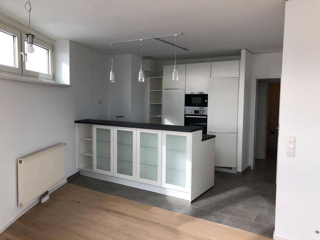 Moderne Küche mit weißer Einbauküche, Frühstücksbar und integrierten Geräten.