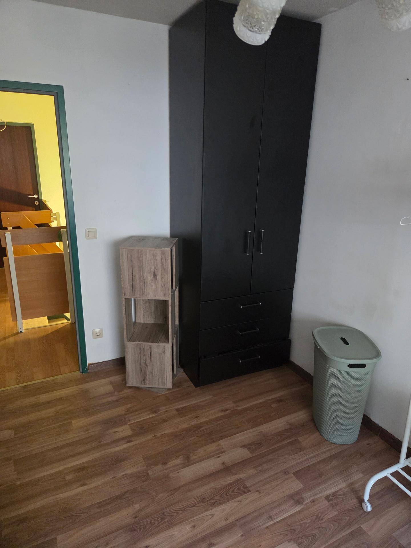 Funktionaler Raum mit großem schwarzen Kleiderschrank und Laminatboden, bietet viel Stauraum.