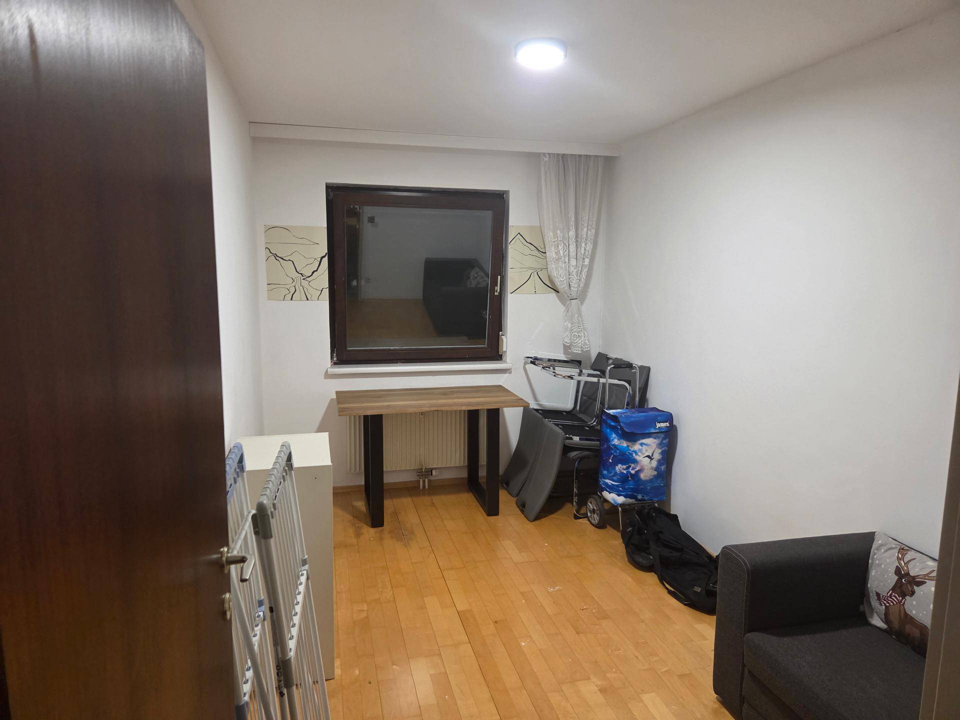 Heller Wohnraum mit Sofa, kleinem Tisch und Laminatboden, vielseitig nutzbar und gut beleuchtet.