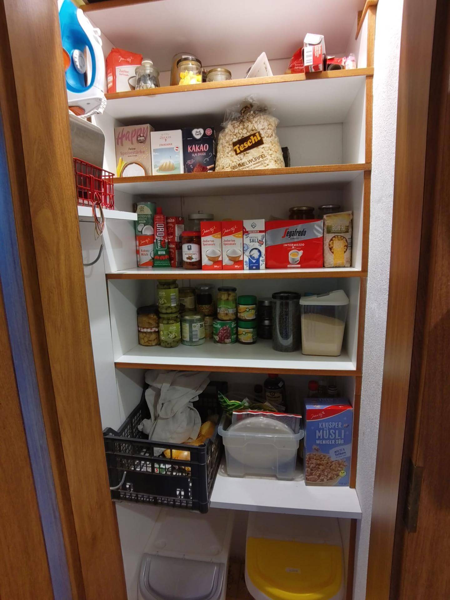Gut organisierte Speisekammer mit Regalen voller Lebensmittel und Haushaltsartikeln.