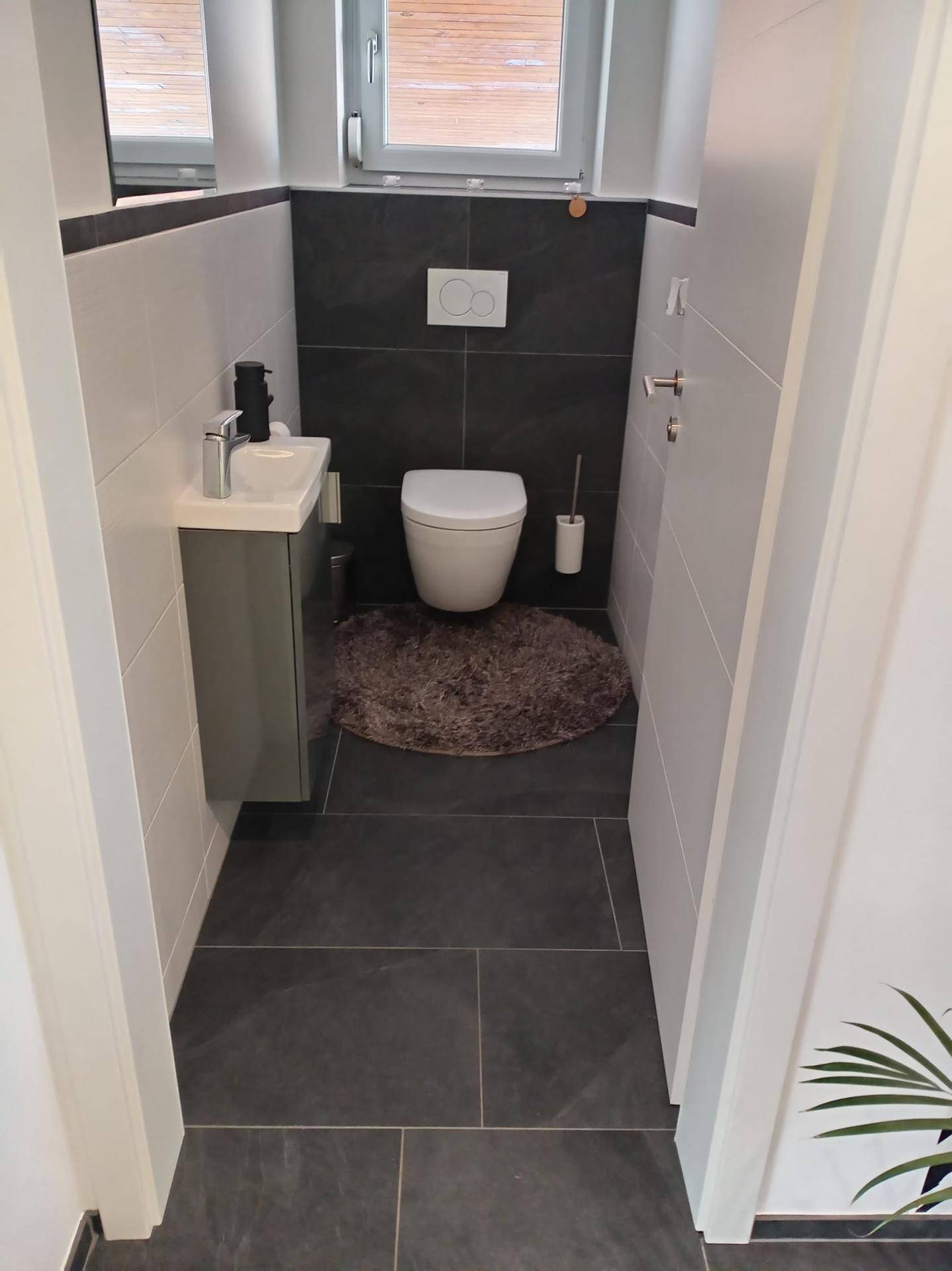 Modernes Gäste-WC mit wandhängendem WC, kleinem Waschbecken und Fenster.