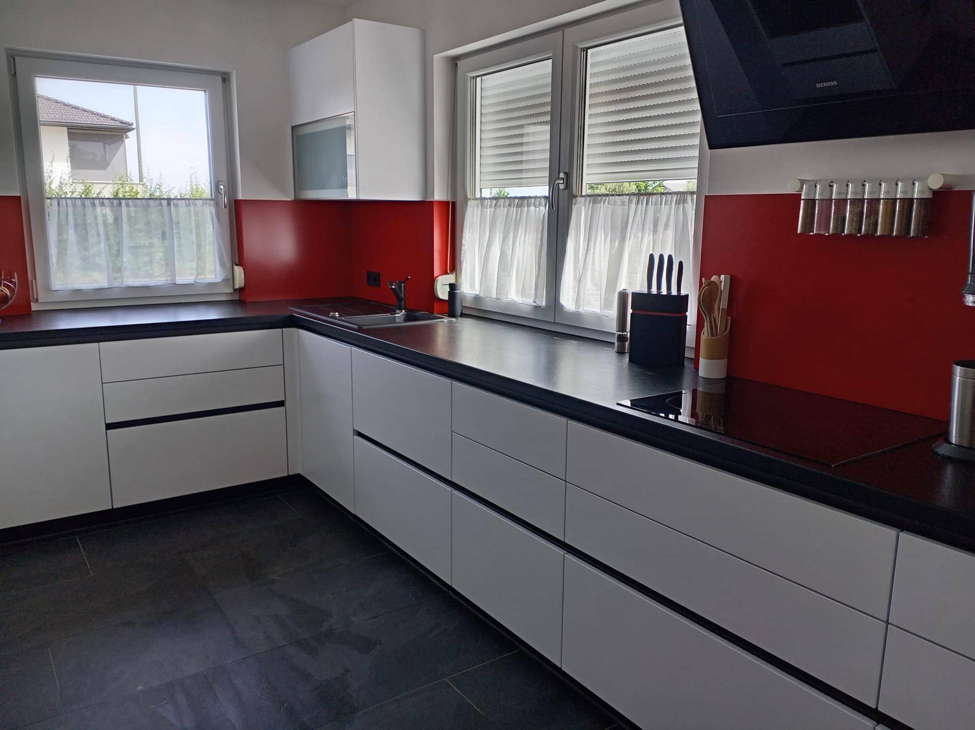 Moderne Küche mit Induktionskochfeld, Dunstabzugshaube und zwei Fenstern für viel Tageslicht.
