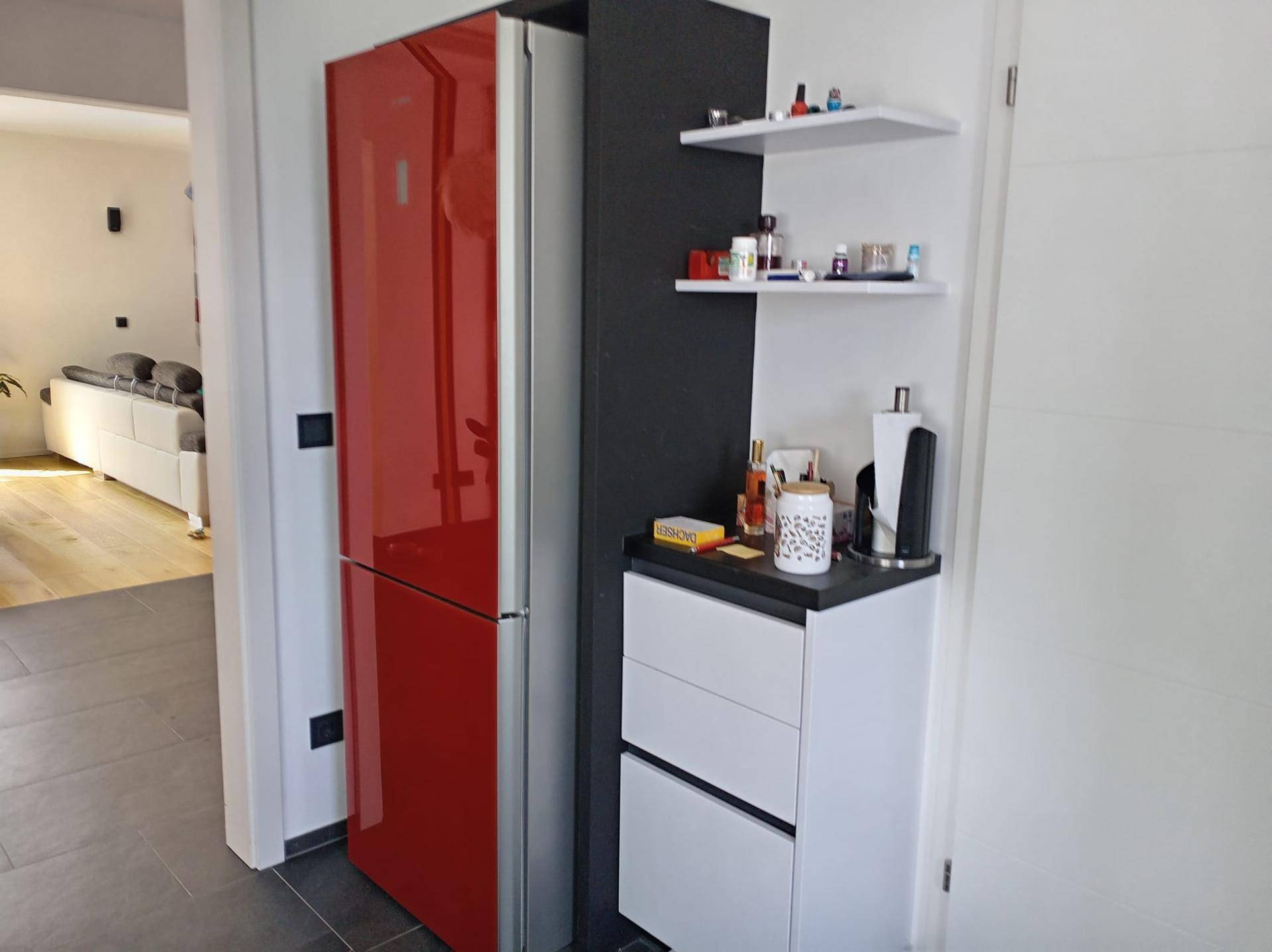Roter Kühlschrank im Flurbereich mit zusätzlichen Ablageflächen und Zugang zum Wohnzimmer.