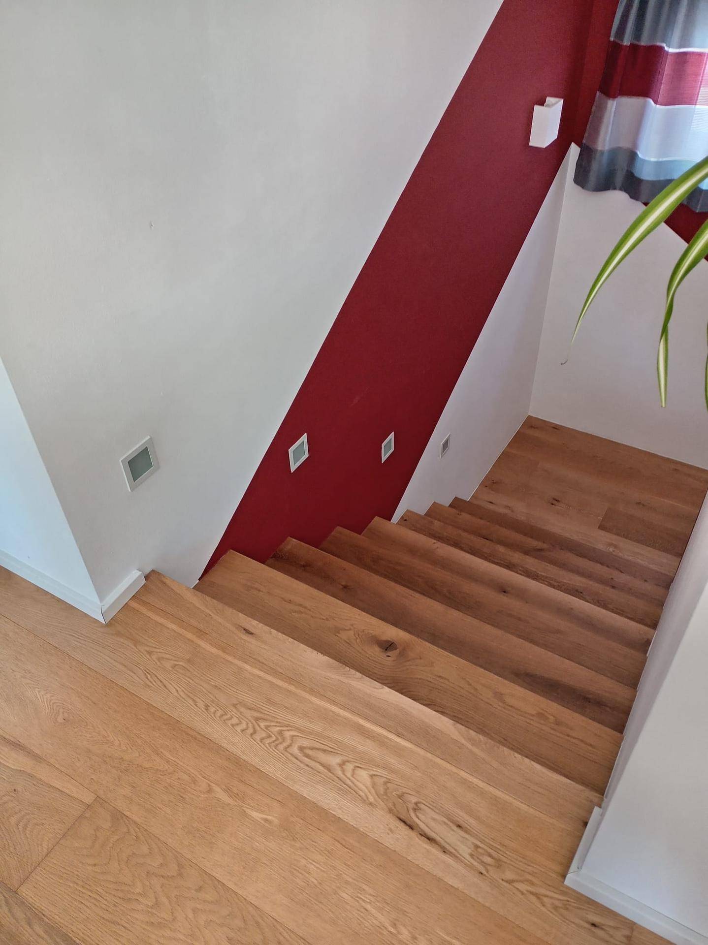 Holztreppe mit roter Akzentwand und integrierter Beleuchtung im modernen Stil.