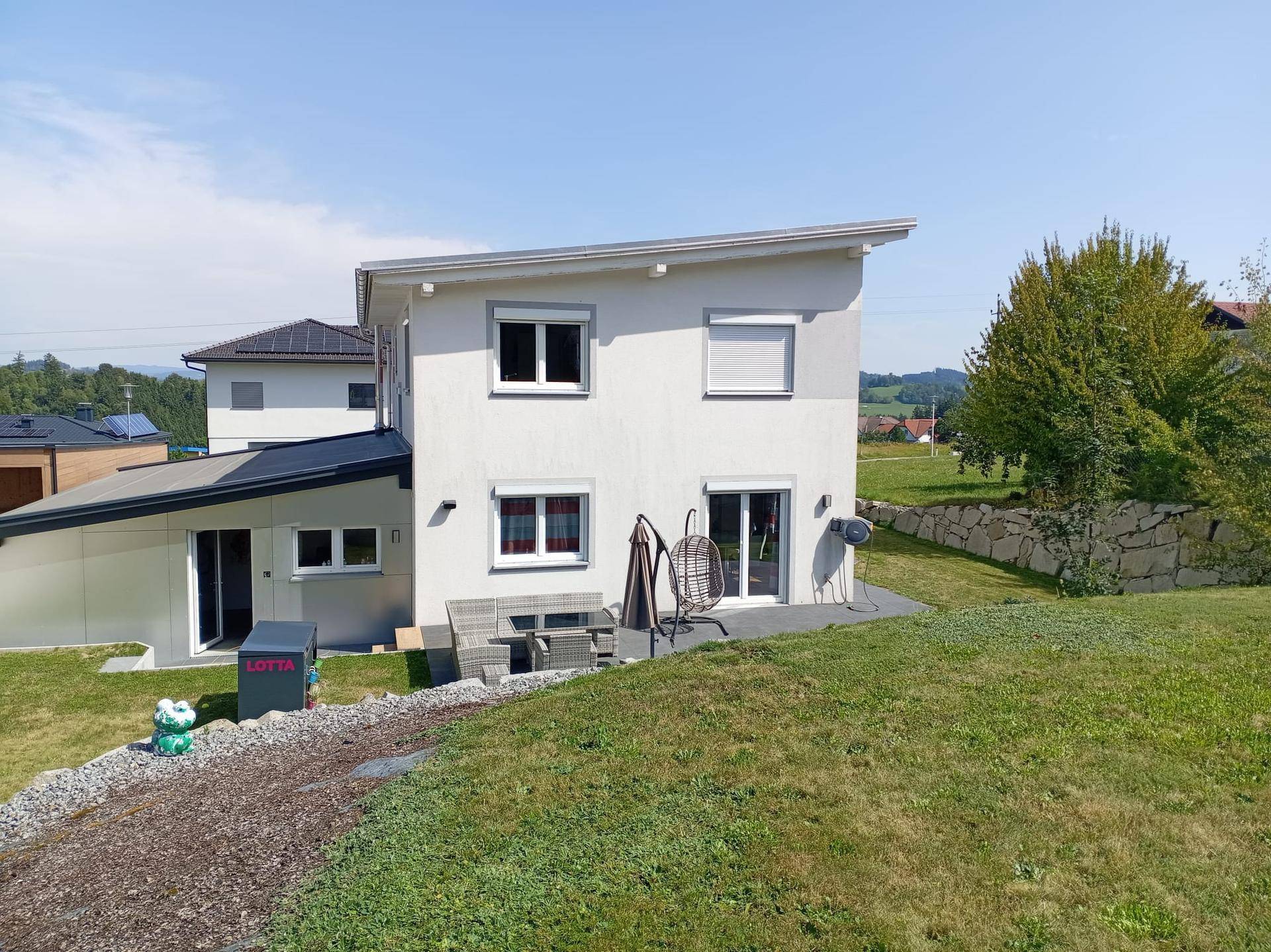 Modernes Einfamilienhaus mit Garten, Terrasse und gepflegter Rasenfläche.