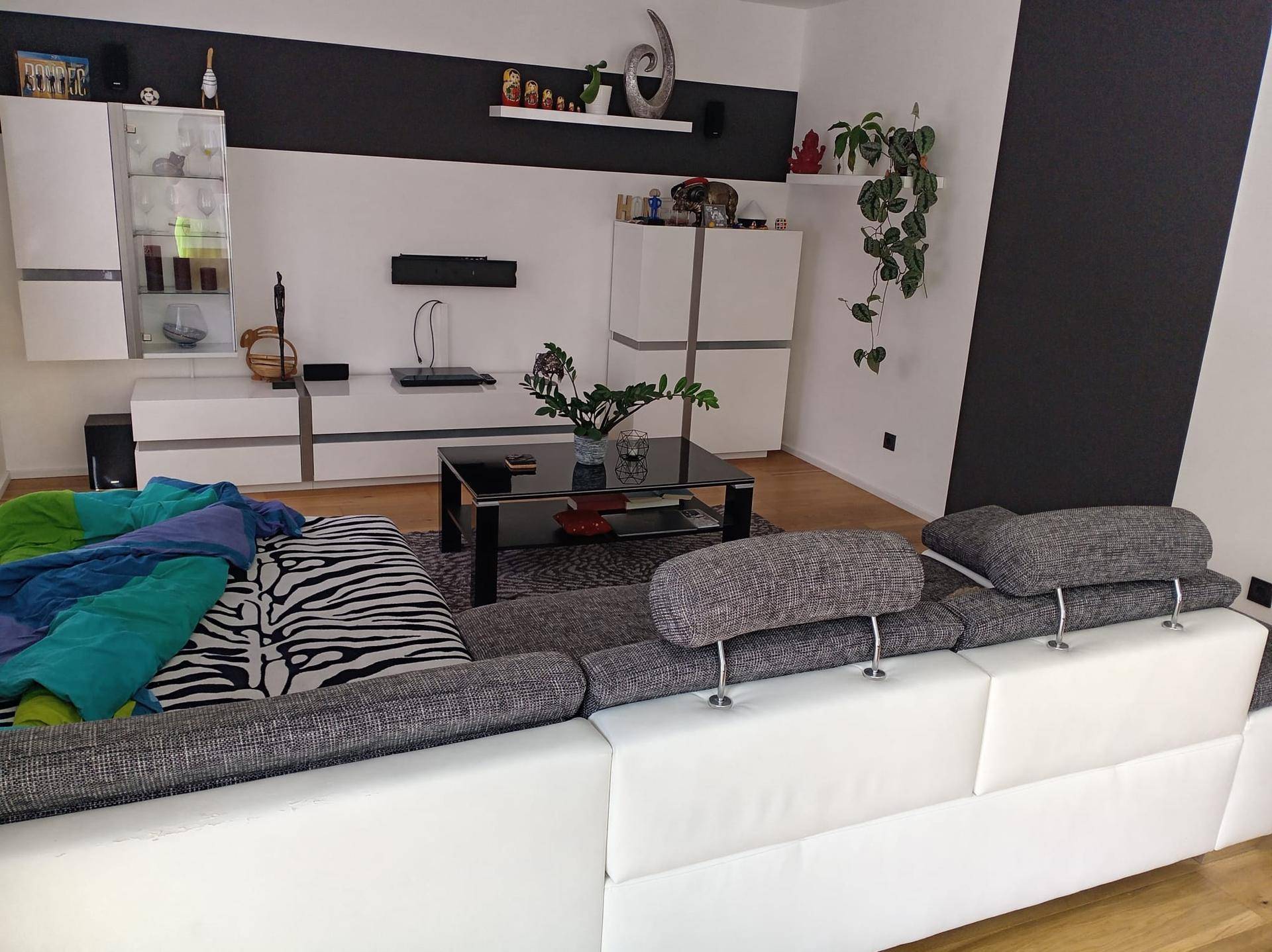 Geräumiges Wohnzimmer mit großem Sofa, Holzboden und moderner Wandgestaltung.