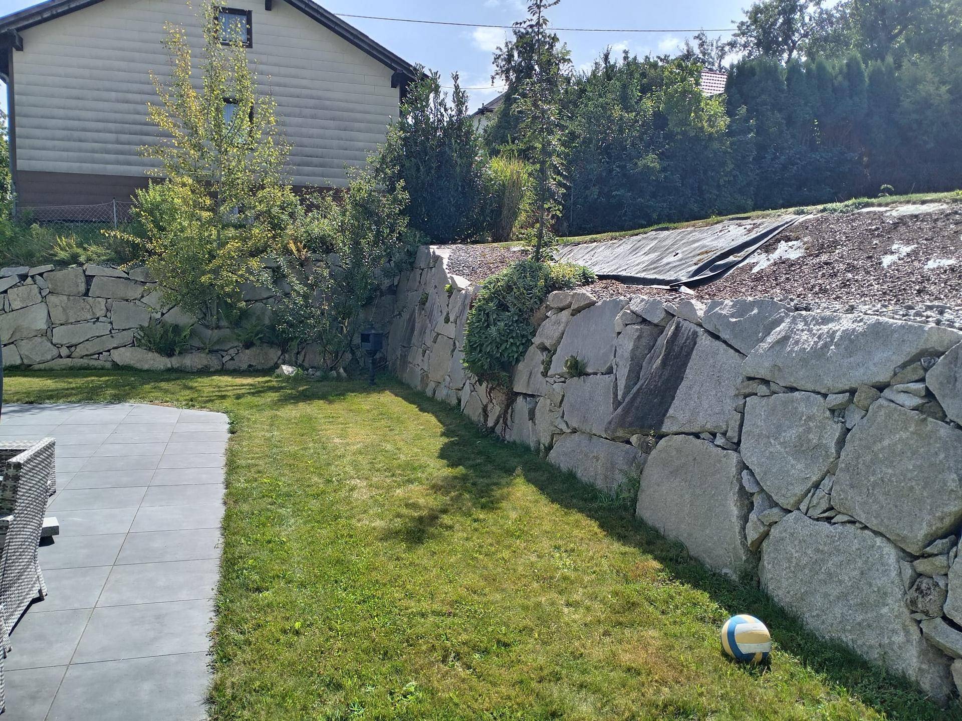 Gepflegter Gartenbereich mit Rasenfläche und dekorativen Steinmauern.