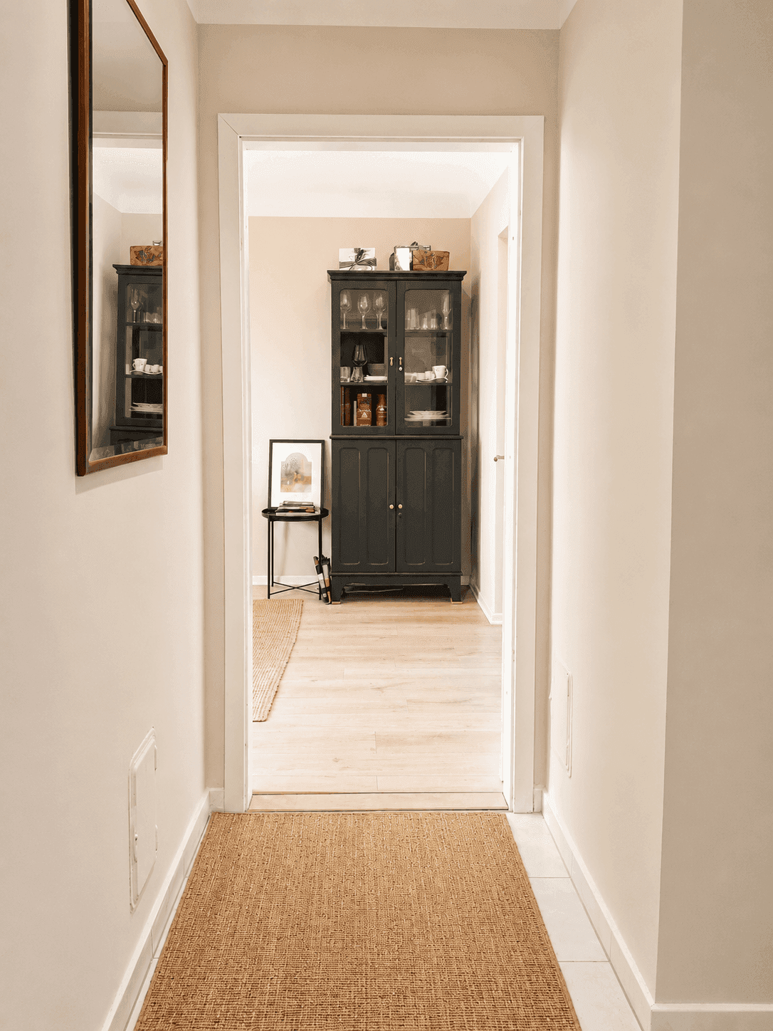 Heller Flur mit Holzboden und einem dunklen Schrank am Ende, der den Übergang zum nächsten Raum markiert.