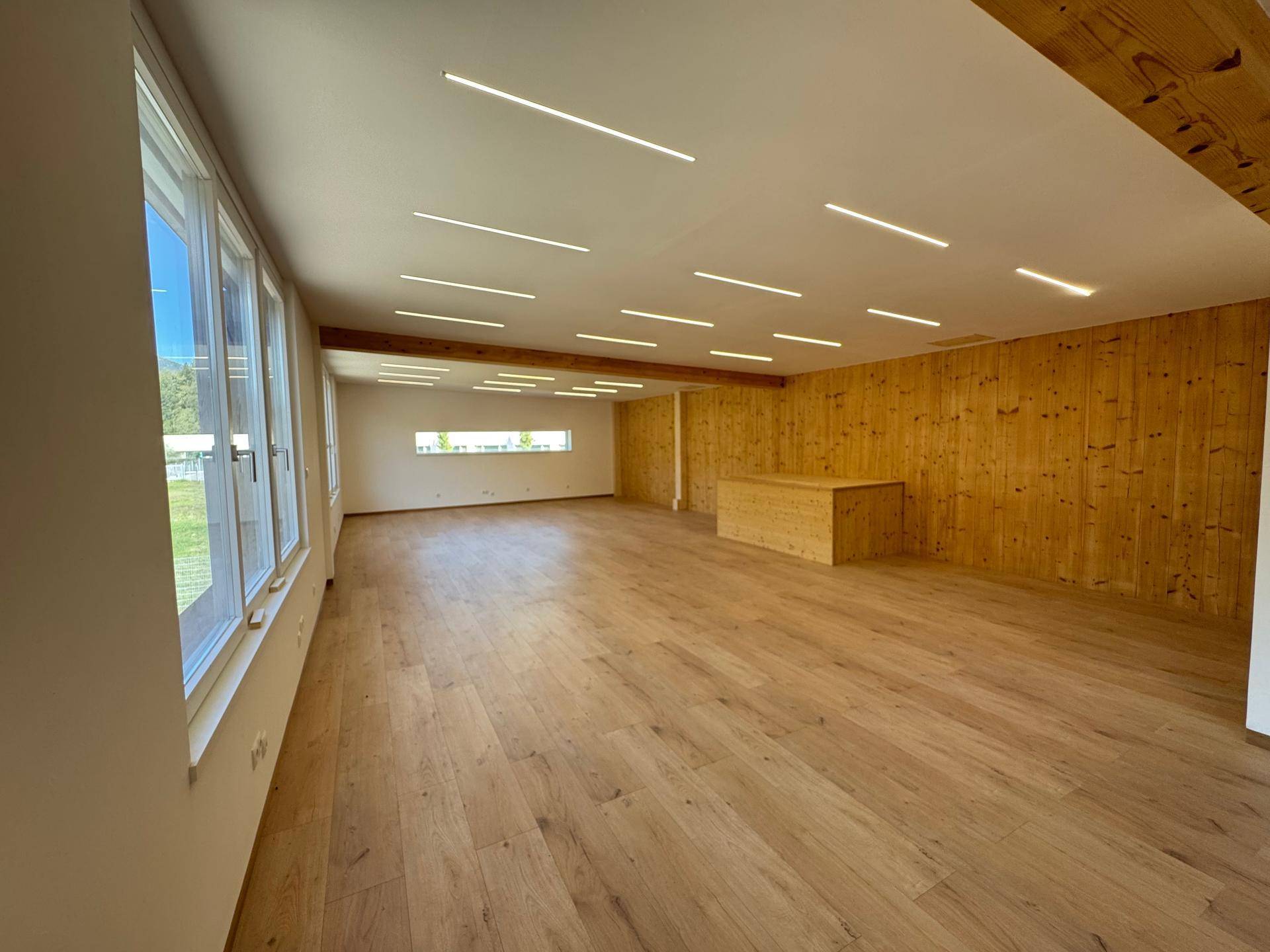 Heller, offener Bürobereich mit Holzboden, Holzvertäfelung und einem Holzelement in der Raummitte.