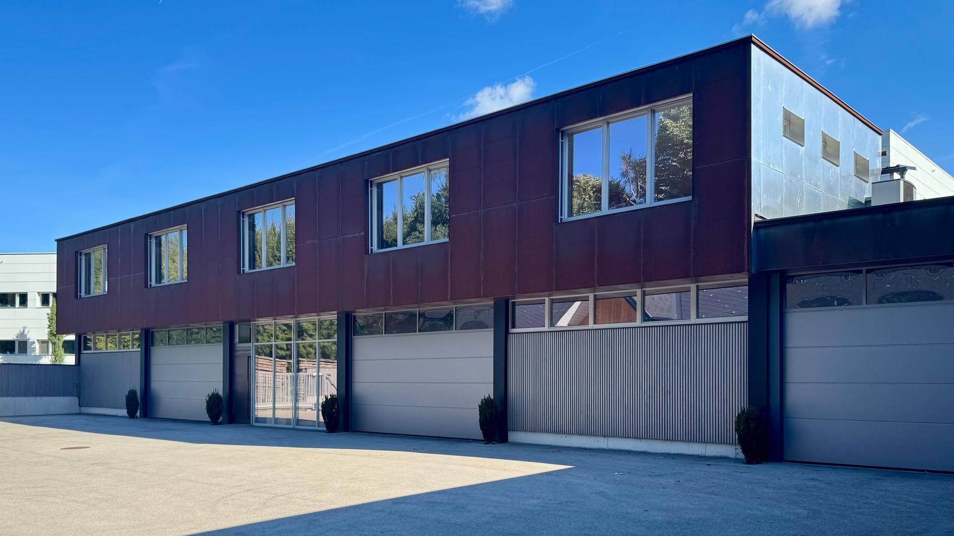 Moderne Gewerbefassade bei Tag mit rostfarbenen Metallplatten und mehreren Garagentoren.
