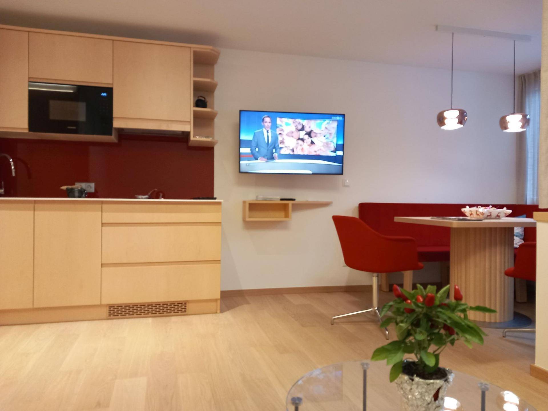 Offener Wohnbereich mit integrierter Küche, Essecke und Flachbildfernseher.