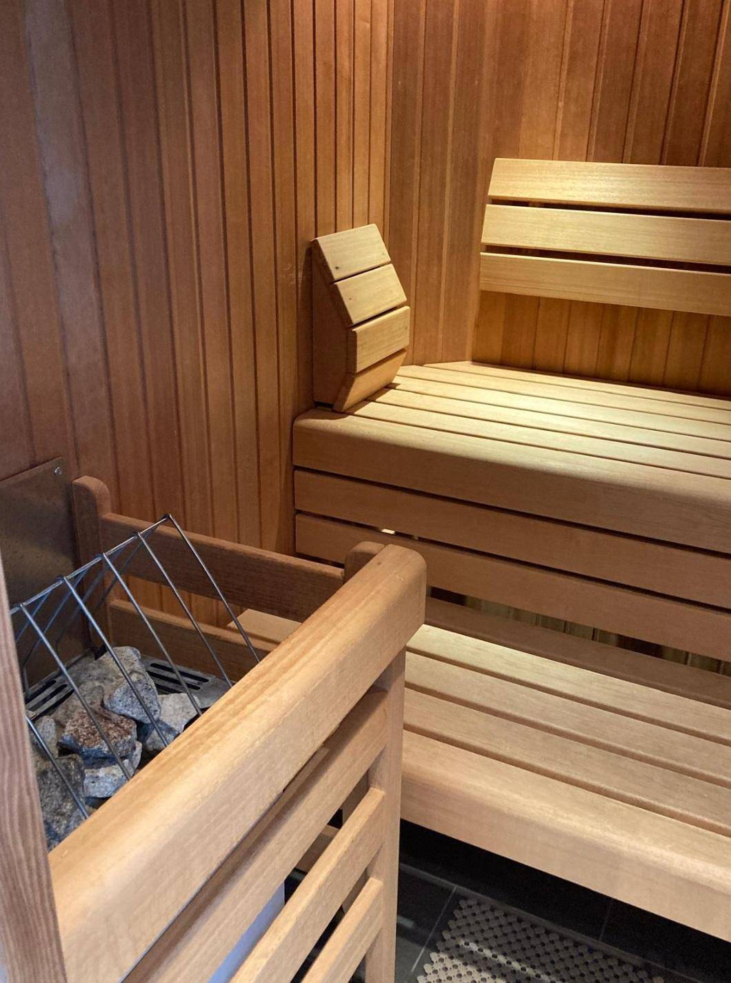 Moderne Holzsauna mit Bänken und Heizofen für entspannende Momente.