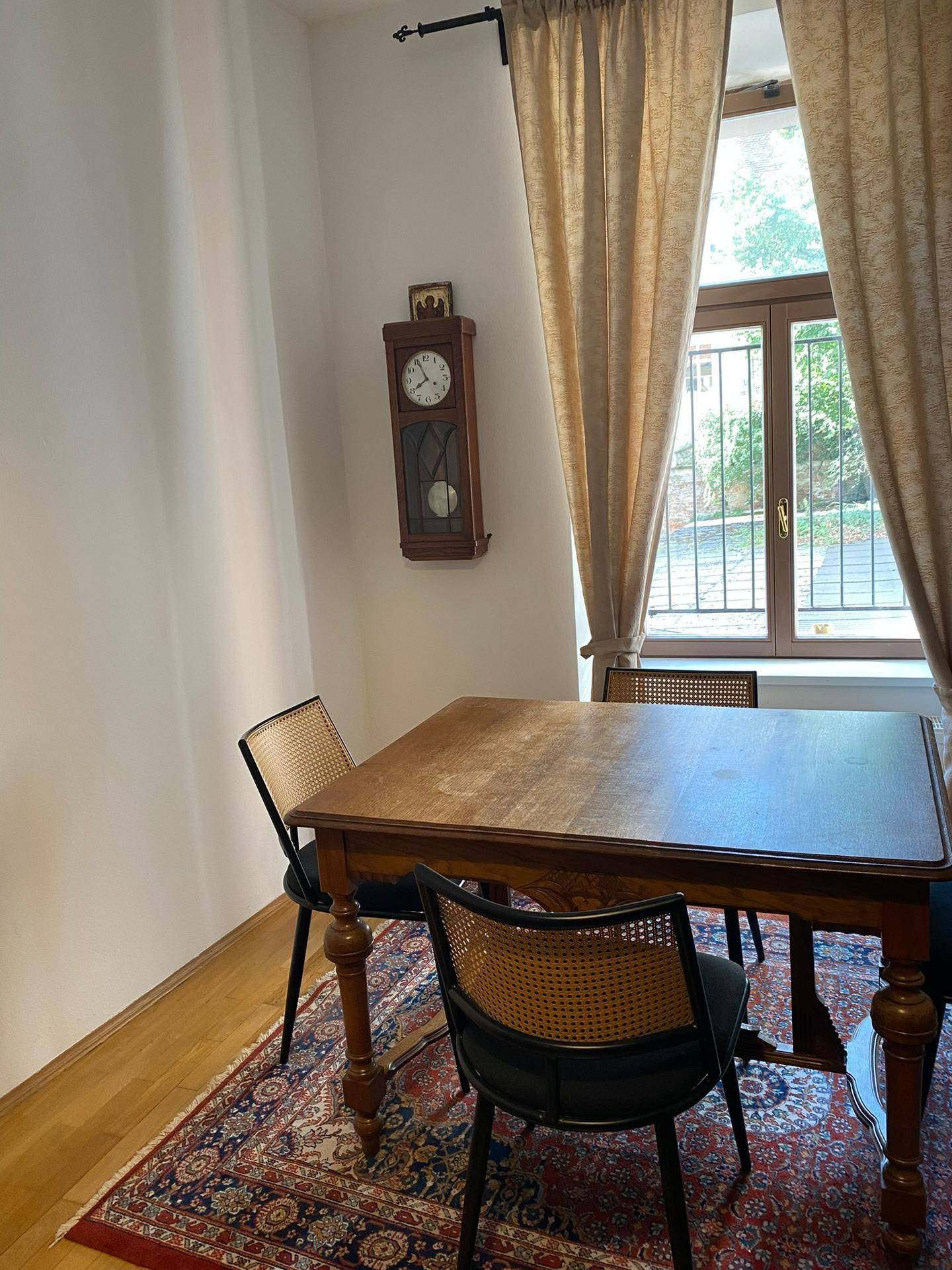 Essbereich mit Holztisch, Stühlen und Fenster mit Vorhängen.