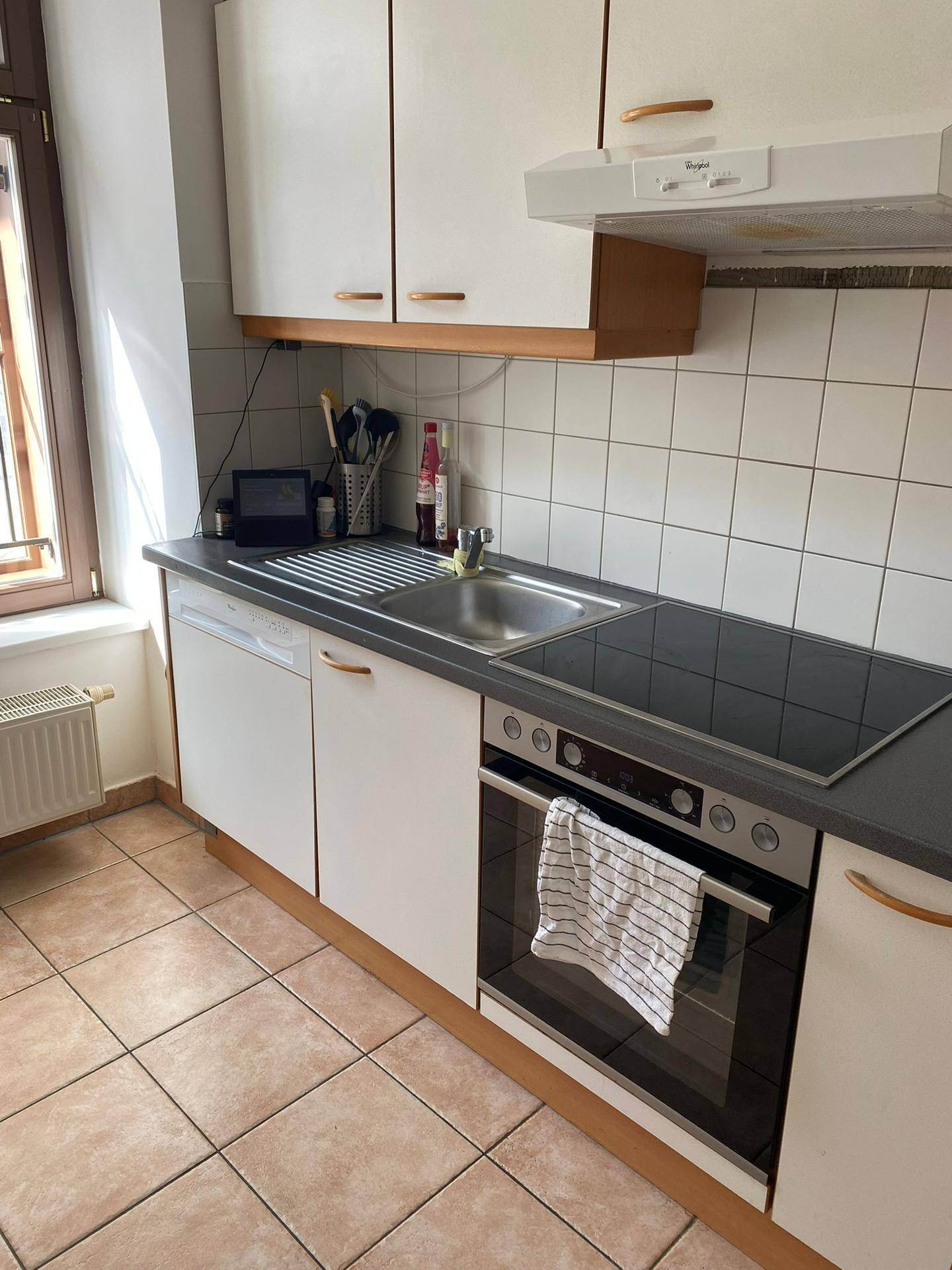 Funktionale Küche mit Einbaugeräten, Spüle und Fliesenboden.