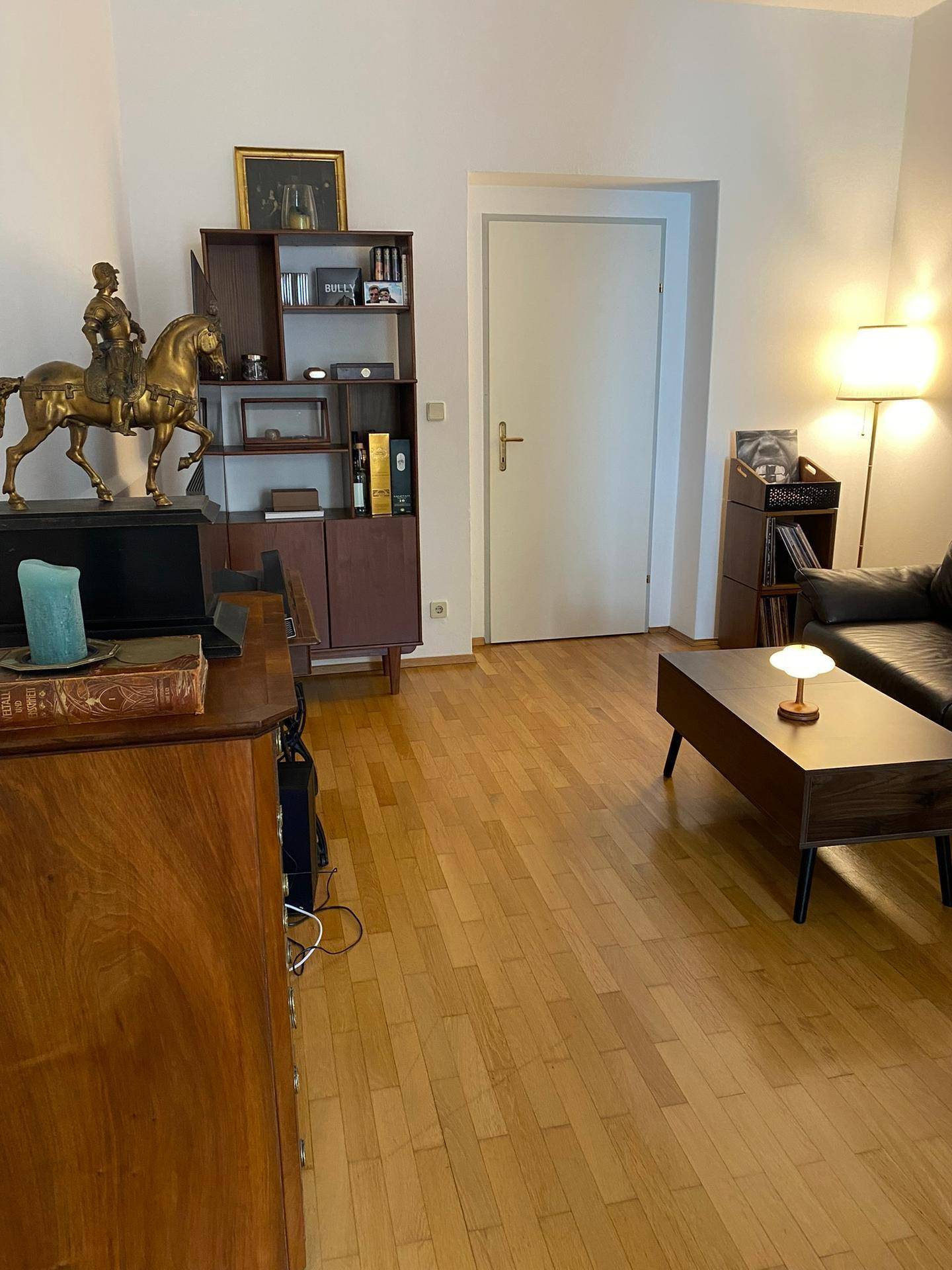 Wohnzimmer mit Holzboden, Ledersofa und einem dekorativen Raumteiler.