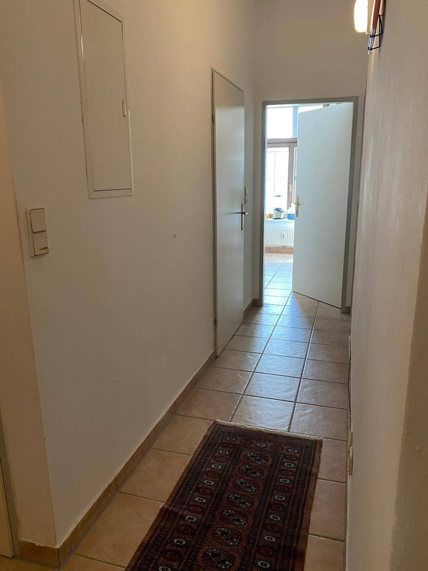 Heller Flur mit Fliesenboden und Zugang zu weiteren Räumen.