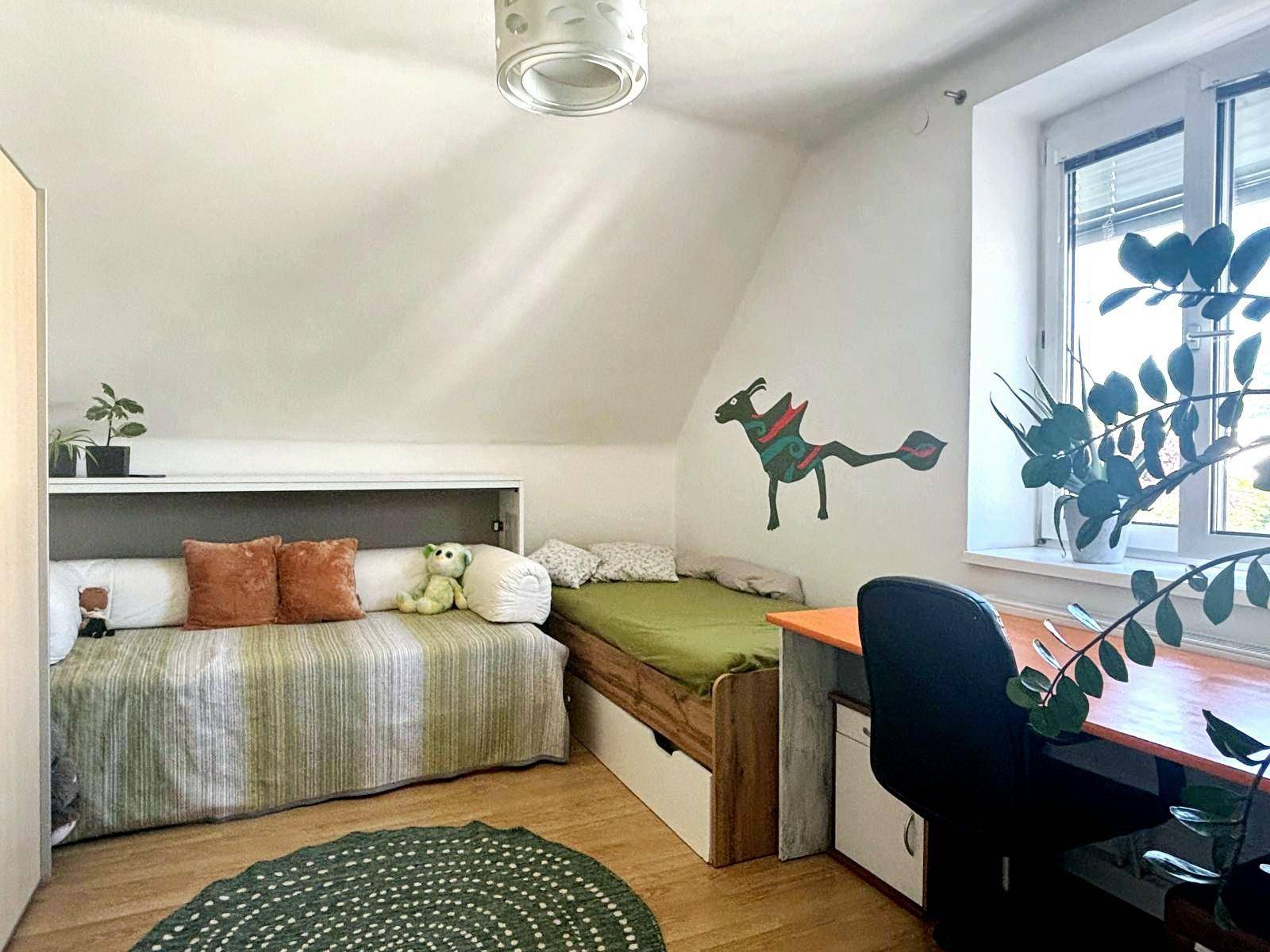 Kinderzimmer mit zwei Betten, Schreibtisch und Fenster, dekoriert mit einer Wandmalerei.