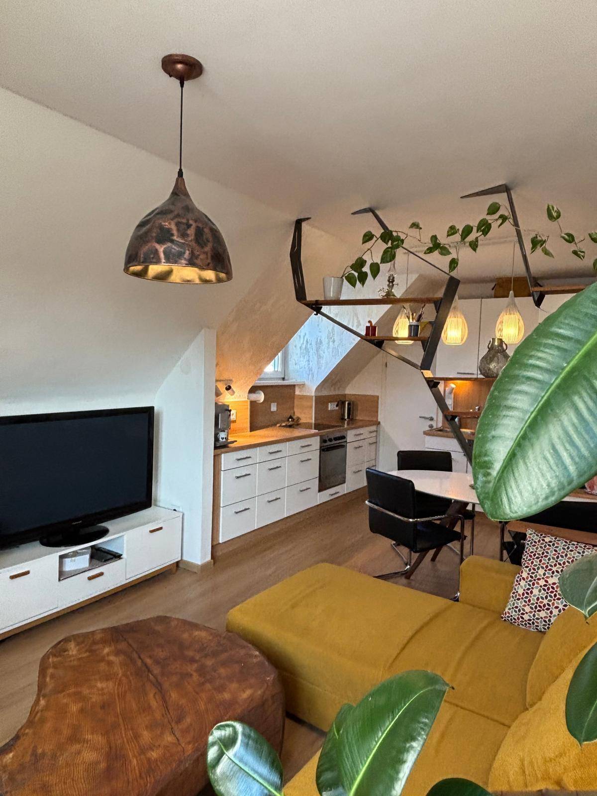 Heller Wohnbereich mit offener Küche, bequemer Couch und Blick auf die dekorative Treppe.