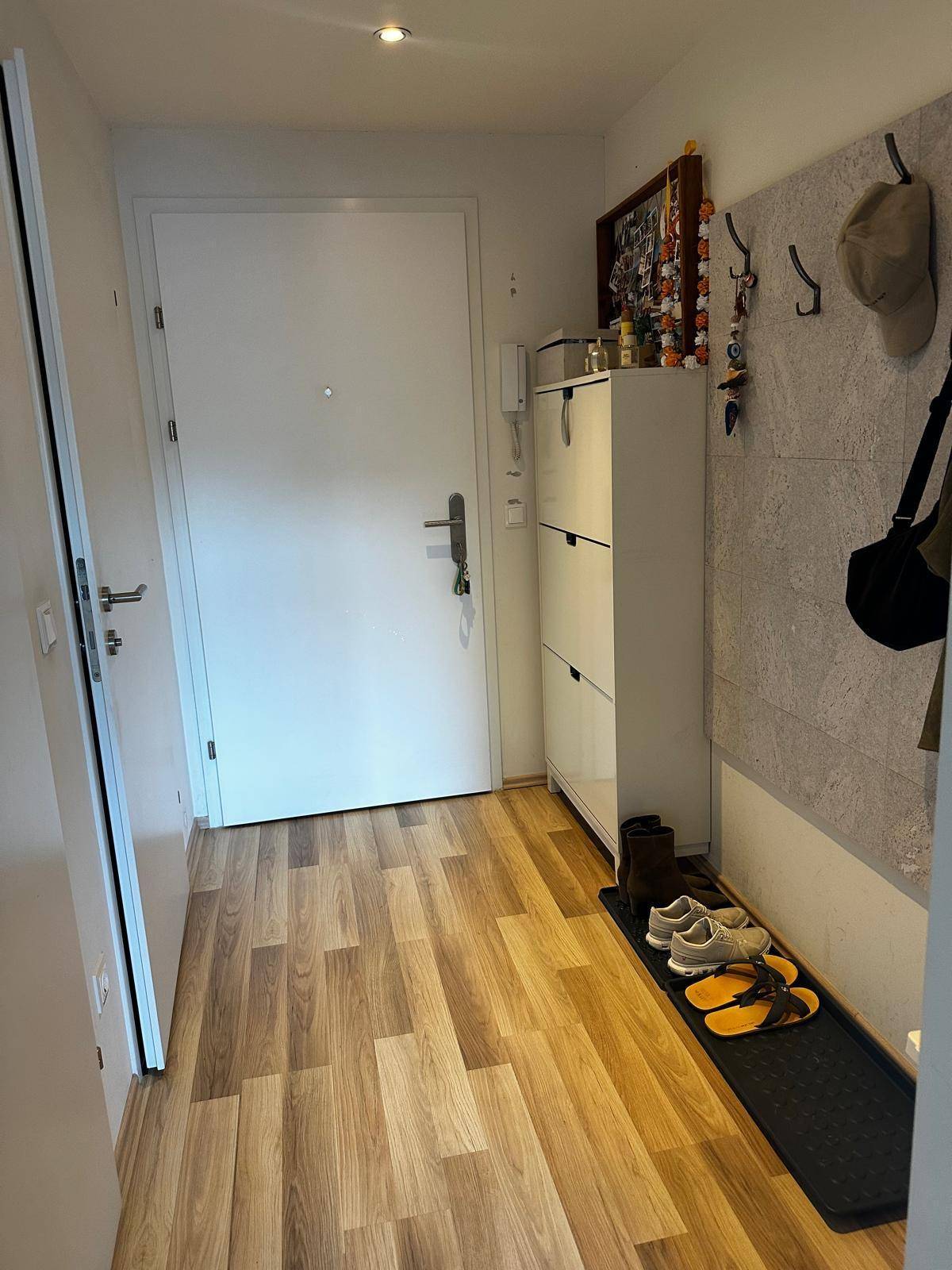 Heller Eingangsbereich mit Laminatboden, Schuhschrank und Garderobe.