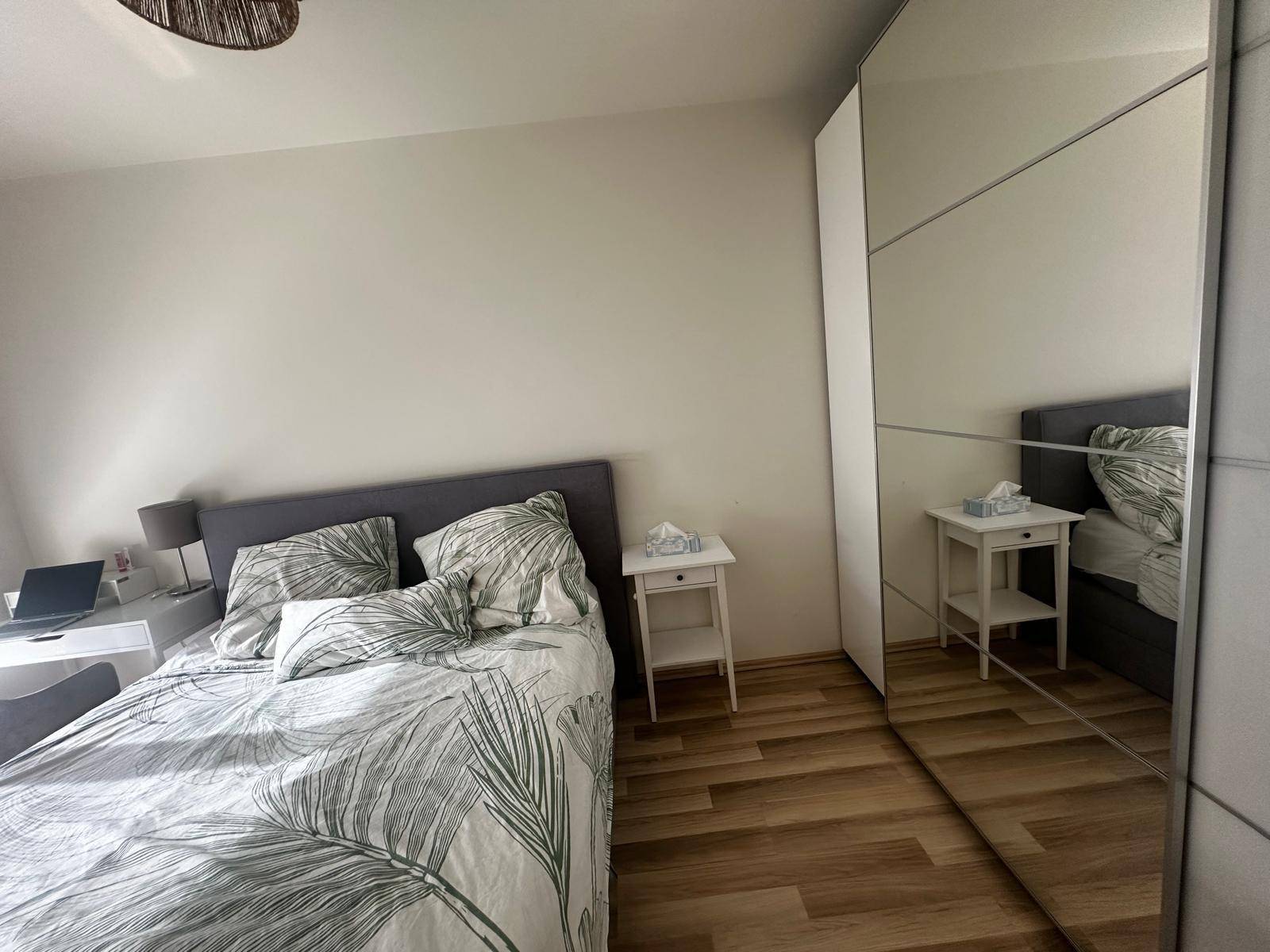 Schlafzimmer mit Doppelbett, Nachttisch und großem Spiegelschrank.