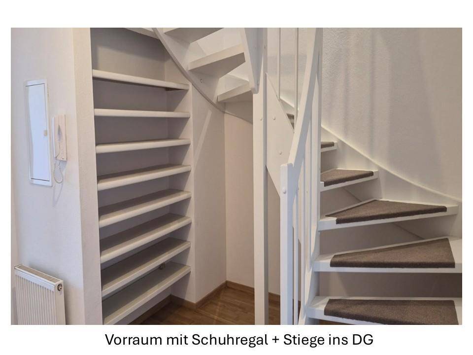 Eingangsbereich mit weißer Wendeltreppe, integriertem Schuhregal und Holzboden.