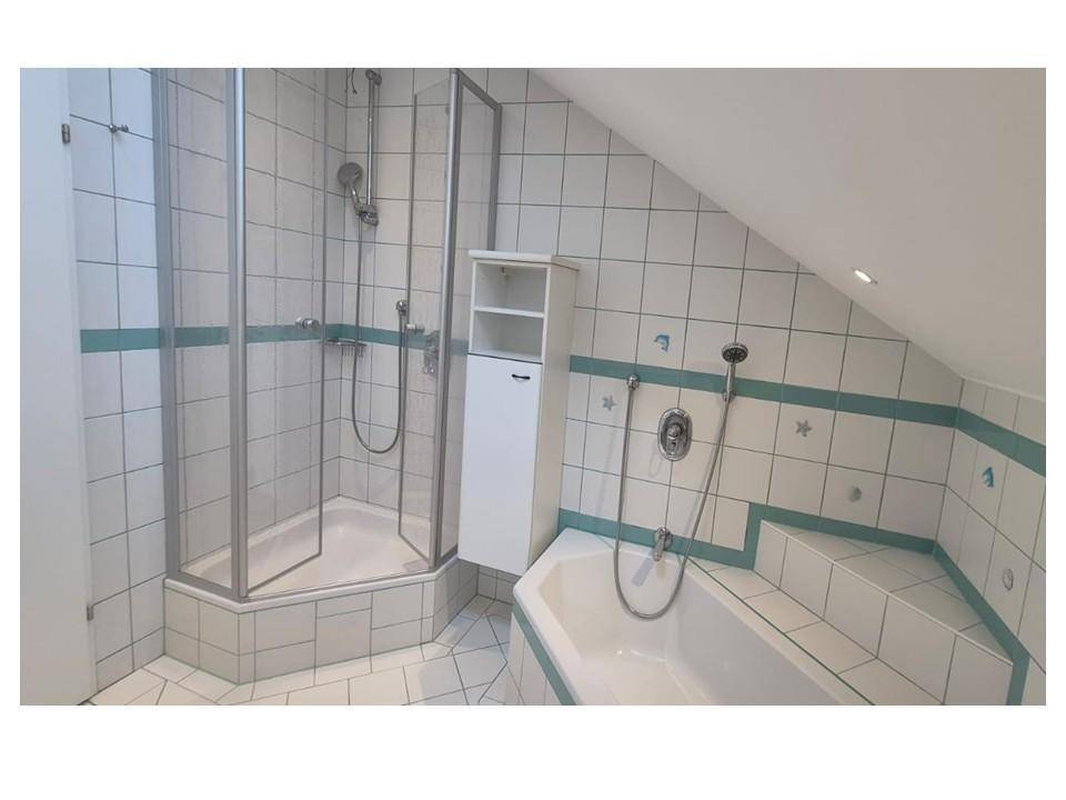 Geräumiges Badezimmer mit Duschkabine, Eckbadewanne und Dachschräge.