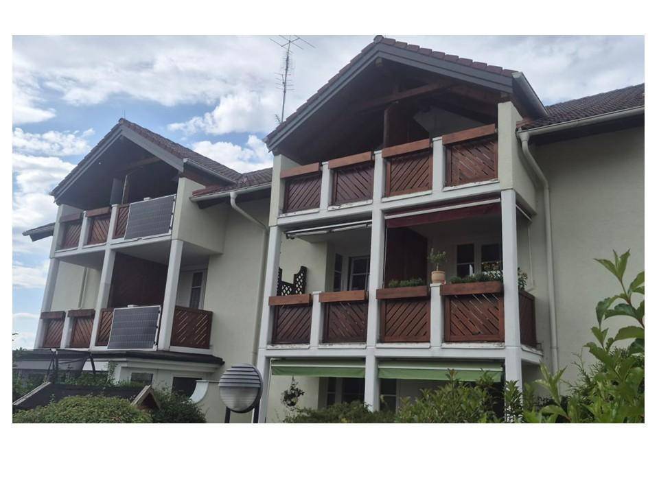 Fassade des Gebäudes mit mehreren Balkonen und Holzgeländern unter leicht bewölktem Himmel.