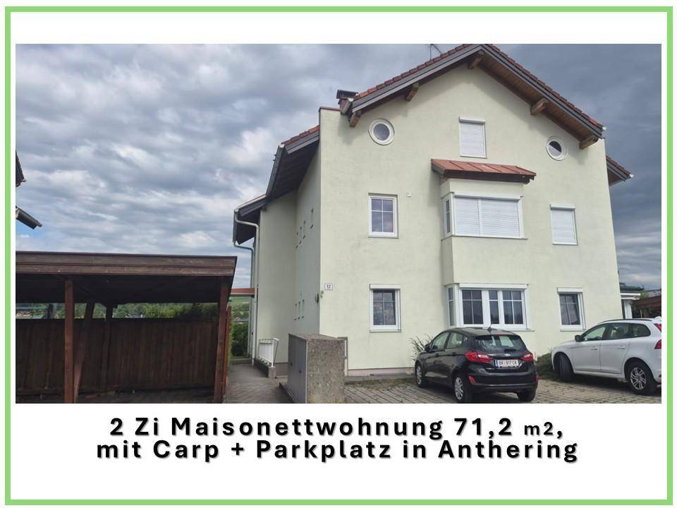 Außenansicht des Mehrfamilienhauses mit Carport und Stellplatz unter bewölktem Himmel.