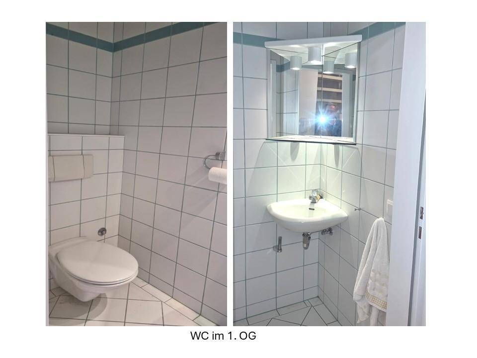 Gäste-WC mit weißen Fliesen, Wand-WC und kleinem Waschbecken mit Spiegelschrank.