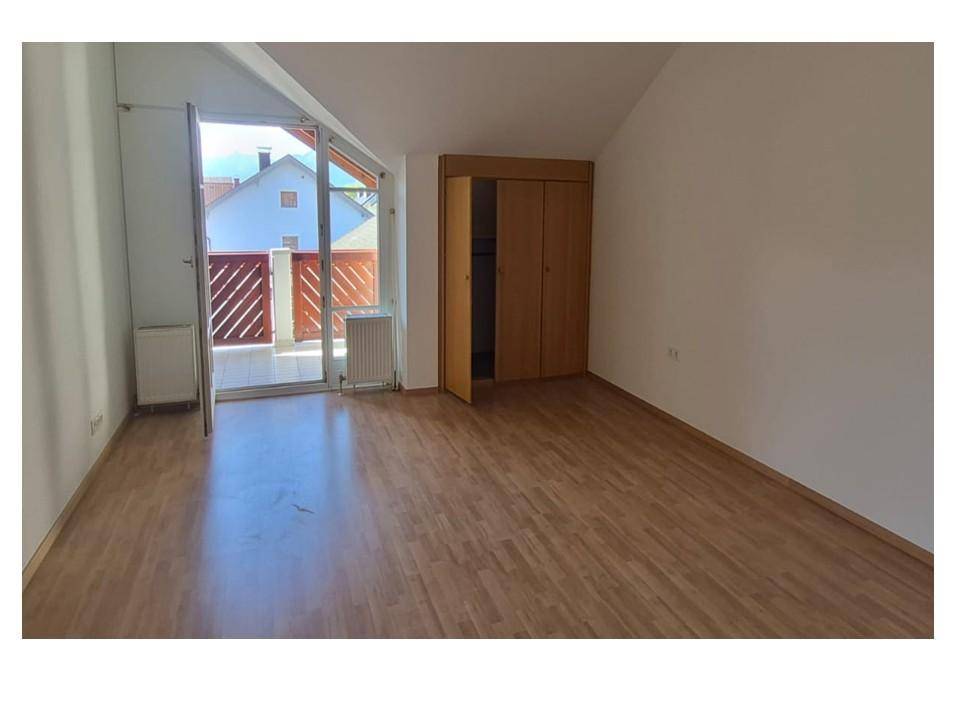 Helles Schlafzimmer mit Holzboden, Kleiderschrank und direktem Zugang zum Balkon.