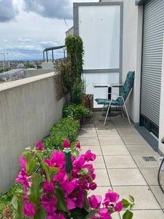 Geflieste Terrasse mit Sitzgelegenheiten, Pflanzen und einem schönen Blick auf die Stadt.