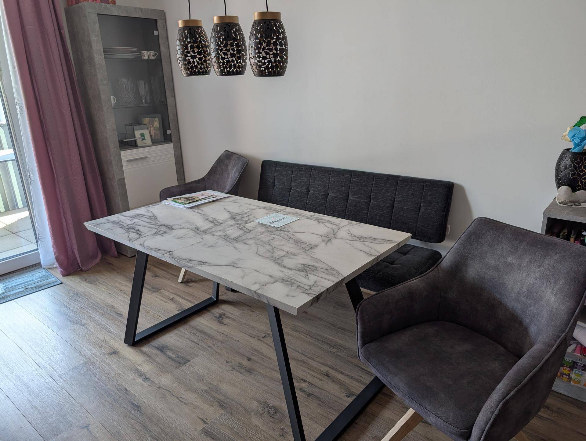 Essbereich mit modernem Tisch, bequemer Sitzbank und Zugang zum Balkon.