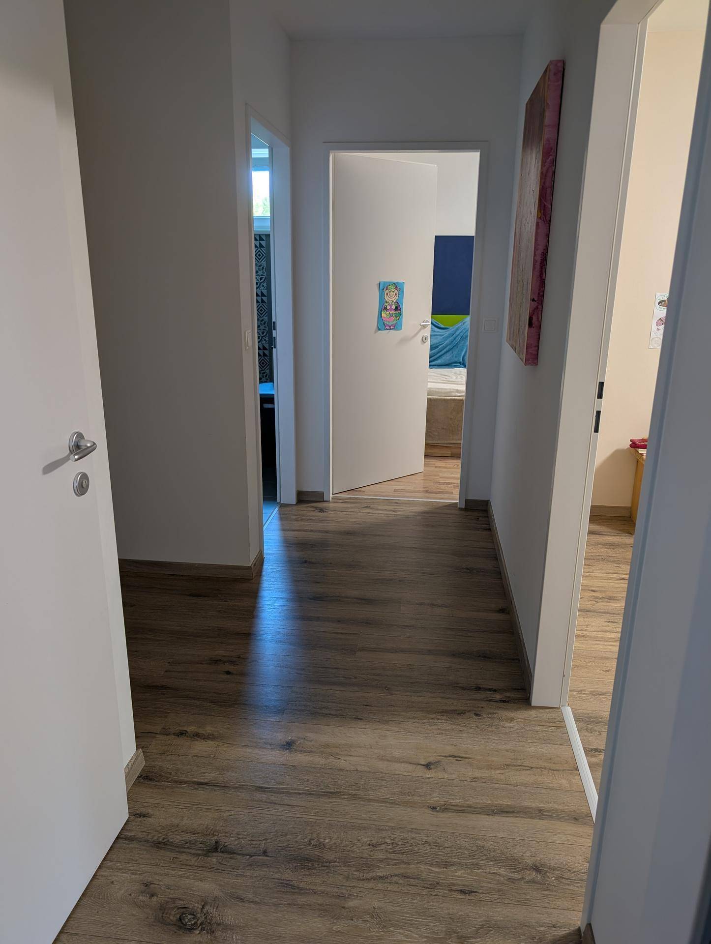 Heller Flur mit Laminatboden, der zu den verschiedenen Zimmern der Wohnung führt.