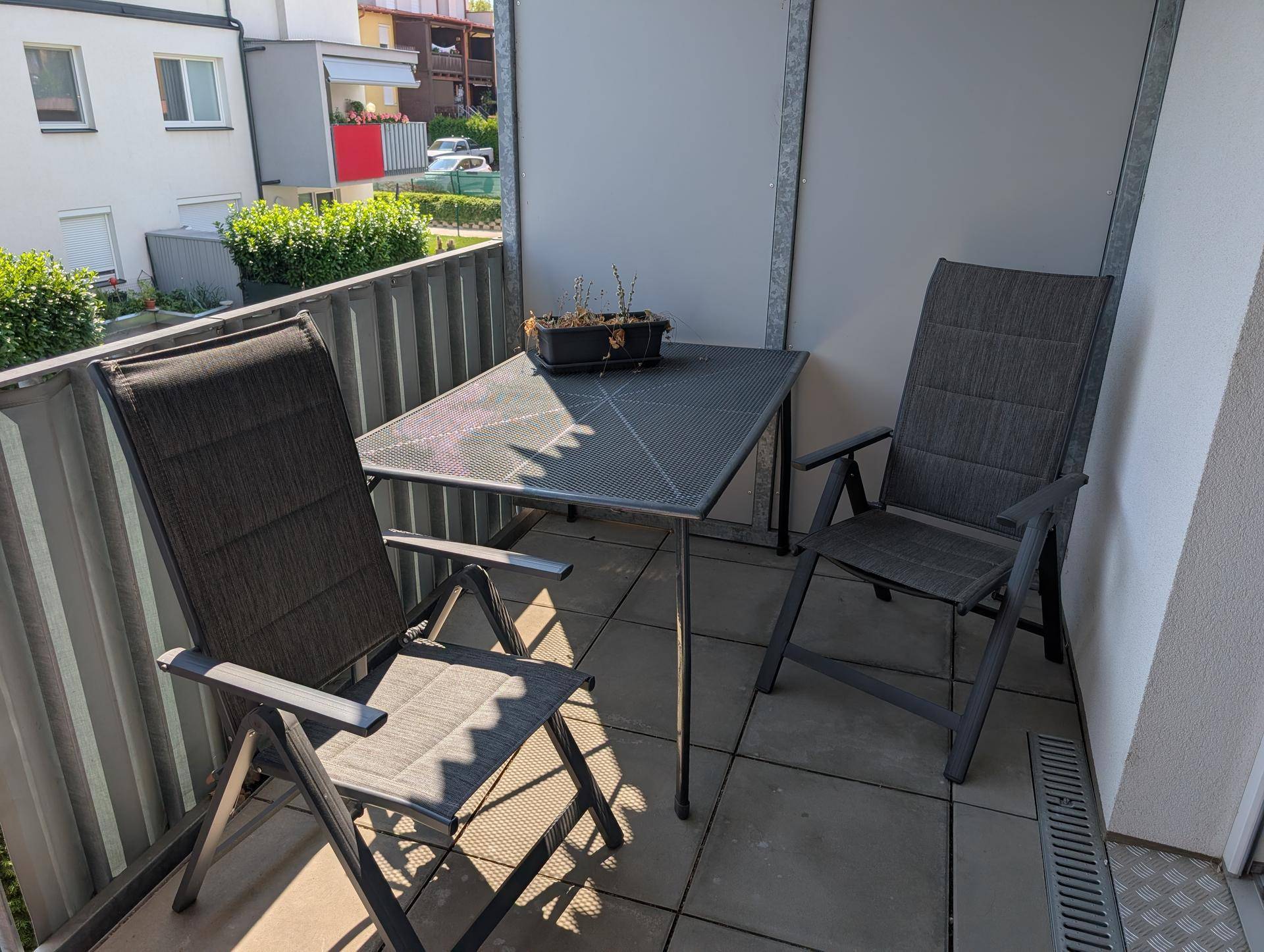 Gemütlicher Balkon mit Tisch und Stühlen, ideal für entspannte Stunden im Freien.
