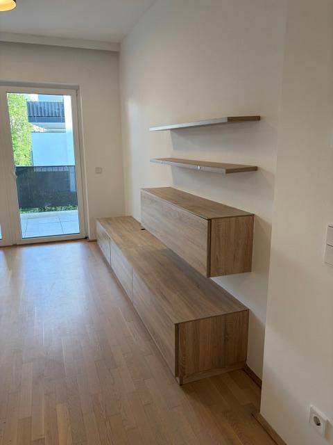 Wohnbereich mit schwebenden Holzregalen und Schränken, Zugang zum Balkon.