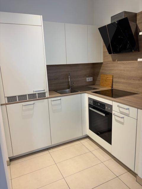 Moderne Einbauküche mit weißen Fronten, Holz-Arbeitsplatte und Induktionskochfeld.